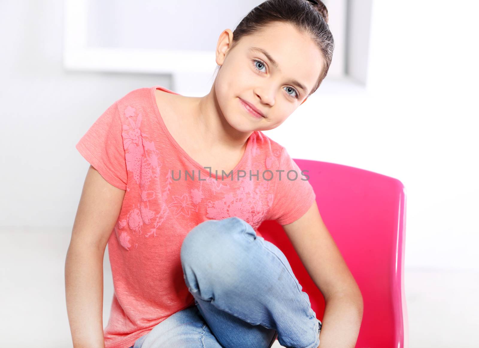 Beautiful girl relaxes on a pink chair dressed in a pink blouse