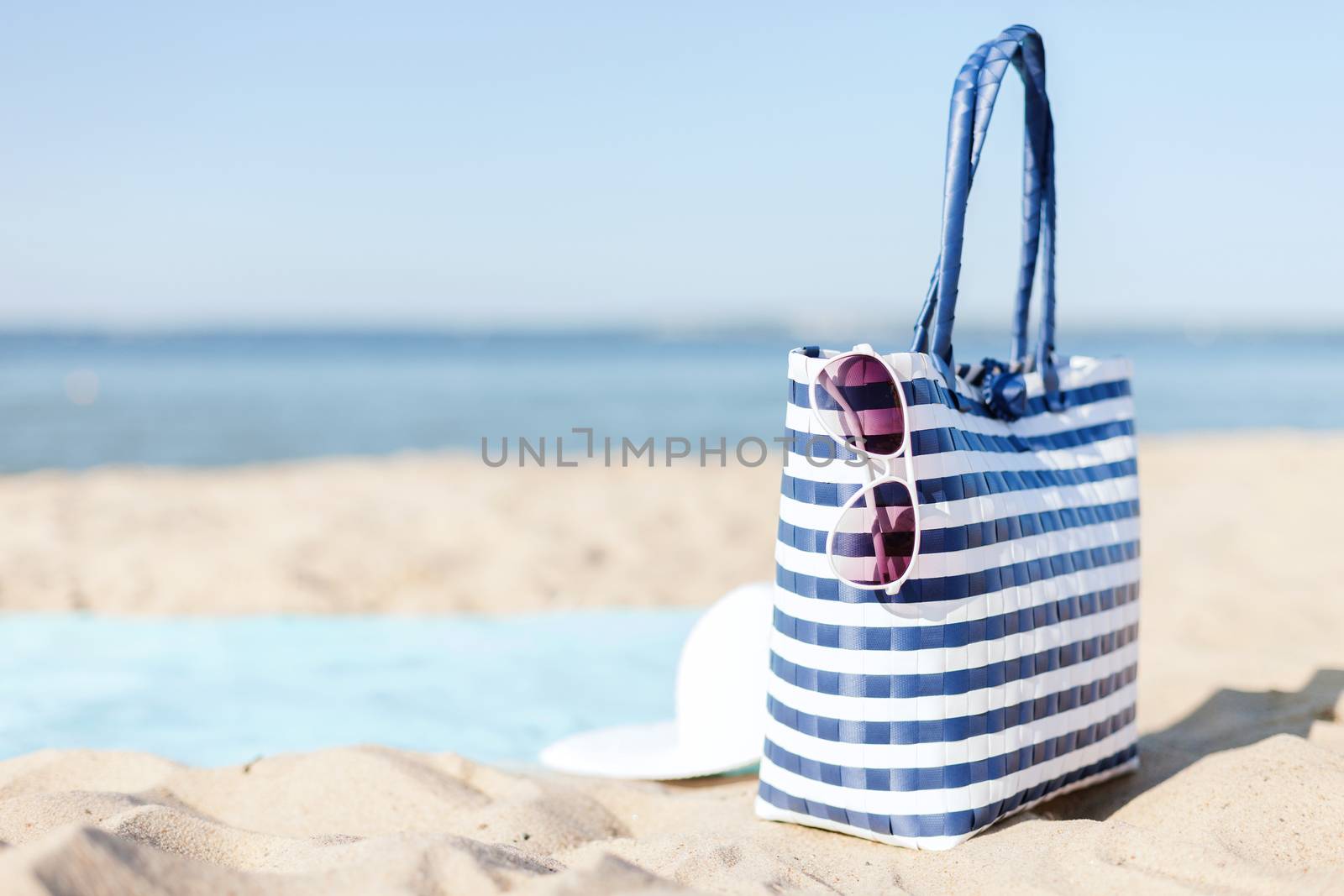 straw hat, sunglasses and bag lying in the sand by dolgachov