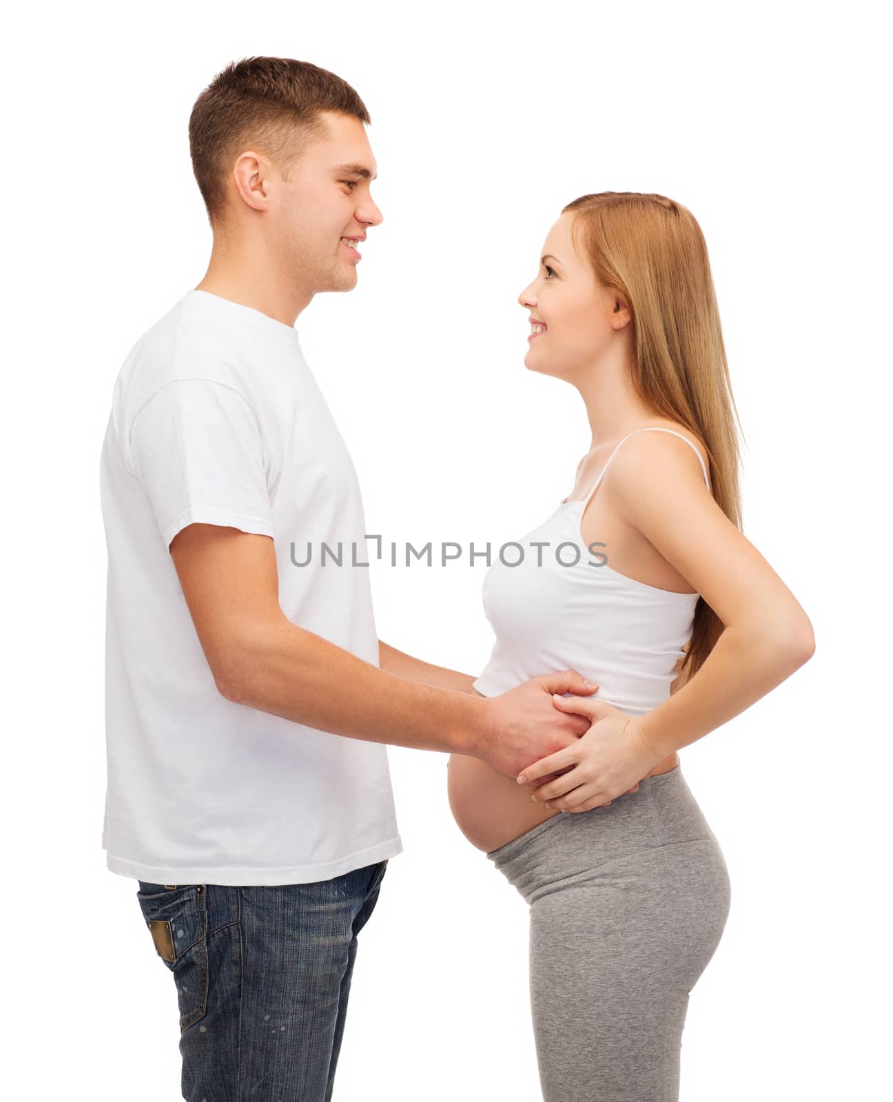 pregnancy, parenthood and happiness concept - happy young family expecting child looking at each other