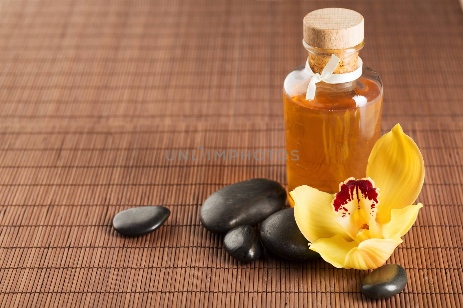 spa, health and beauty concept - closeup of essential oil, massage stones and orchid flower