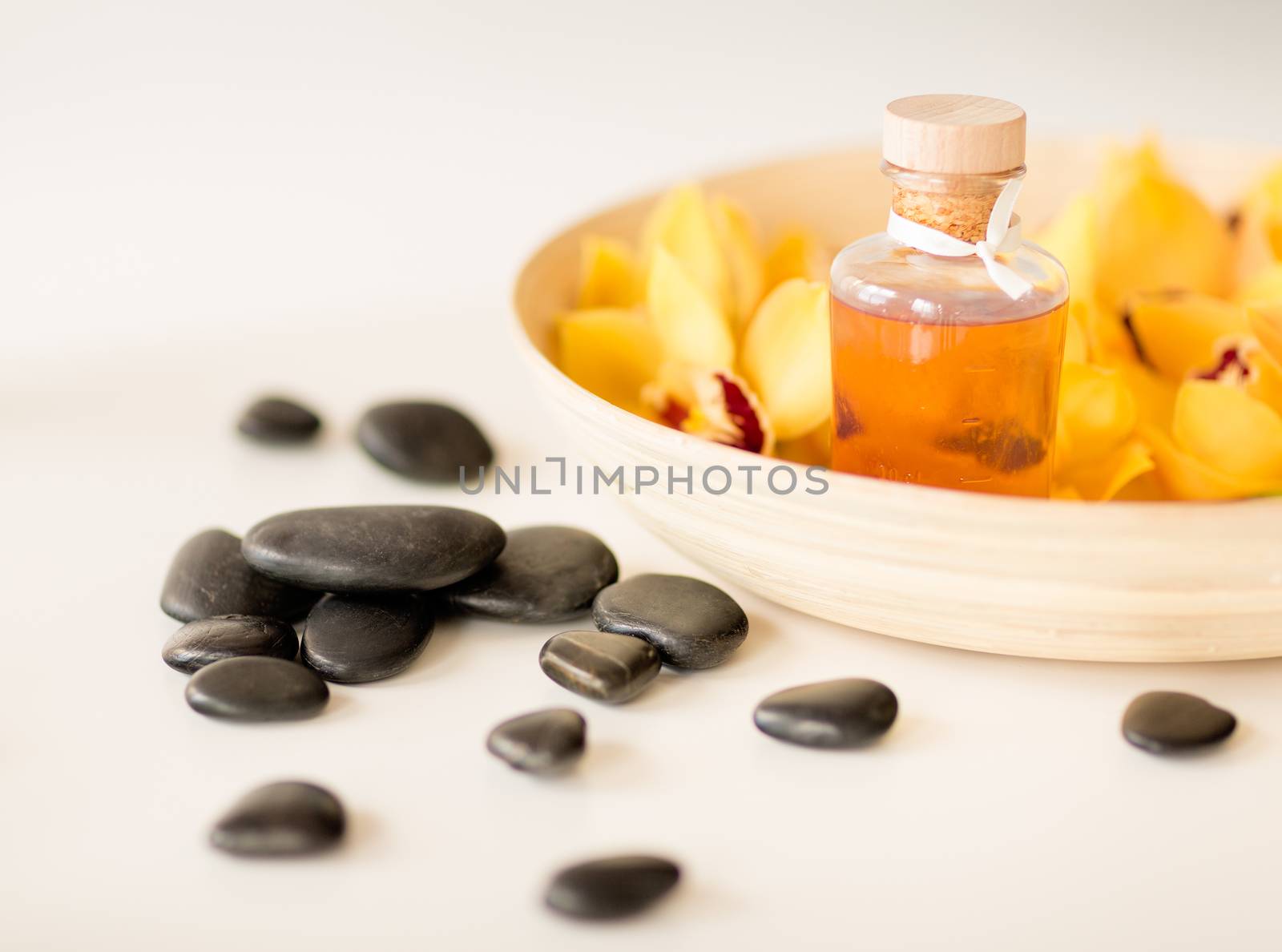 spa, heath and beauty concept - massage stones with orchid flowers on table