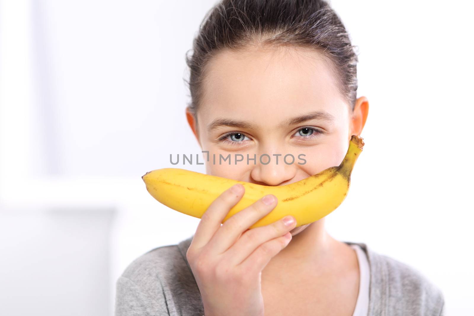 Face of a beautiful young Caucasian girl with banana smile in blue dress on white background