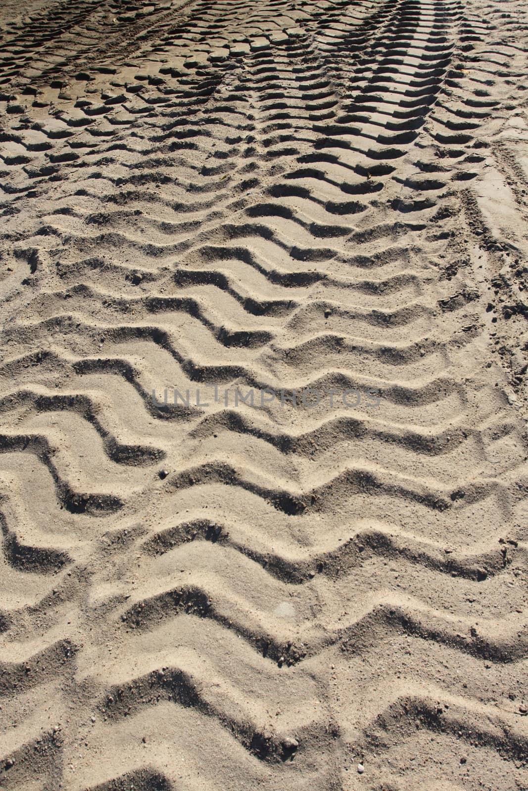 Big heavy tractor wheel tracks in the sand.