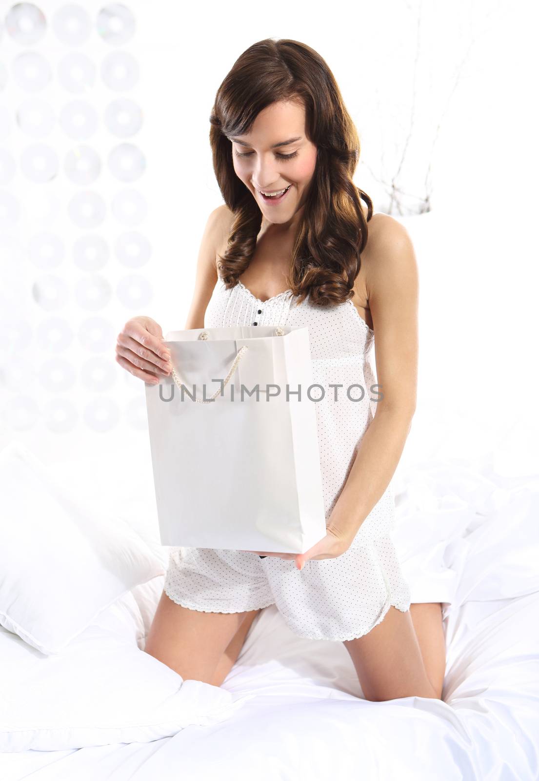 Beautiful young woman watching a watch gift kneeling on the bed