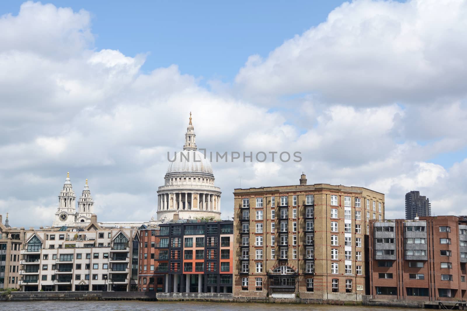 London, UK - May 25, 2014: St Paul's Cathedral and other architecture along the north bank of the Thames on May 25, 2014. Apartments and the Samuel Pepys bar line the riverbank.