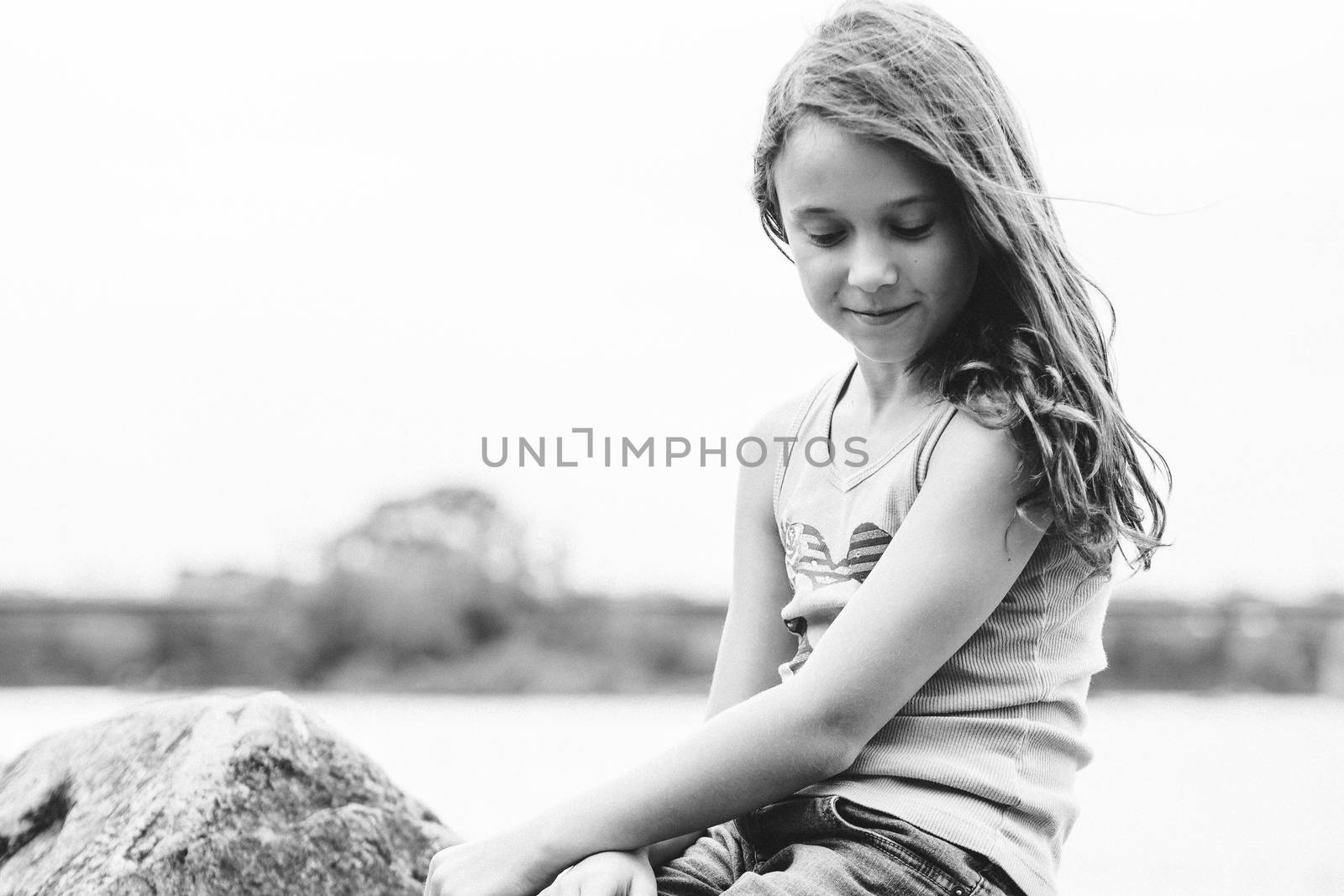 Girl daydreaming sitting on a rock by a river in black and white