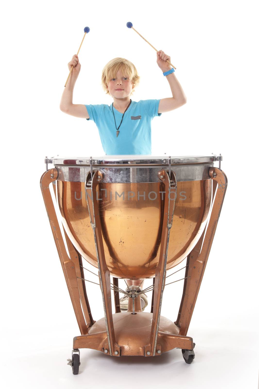 young blond boy playing kettledrum against white background