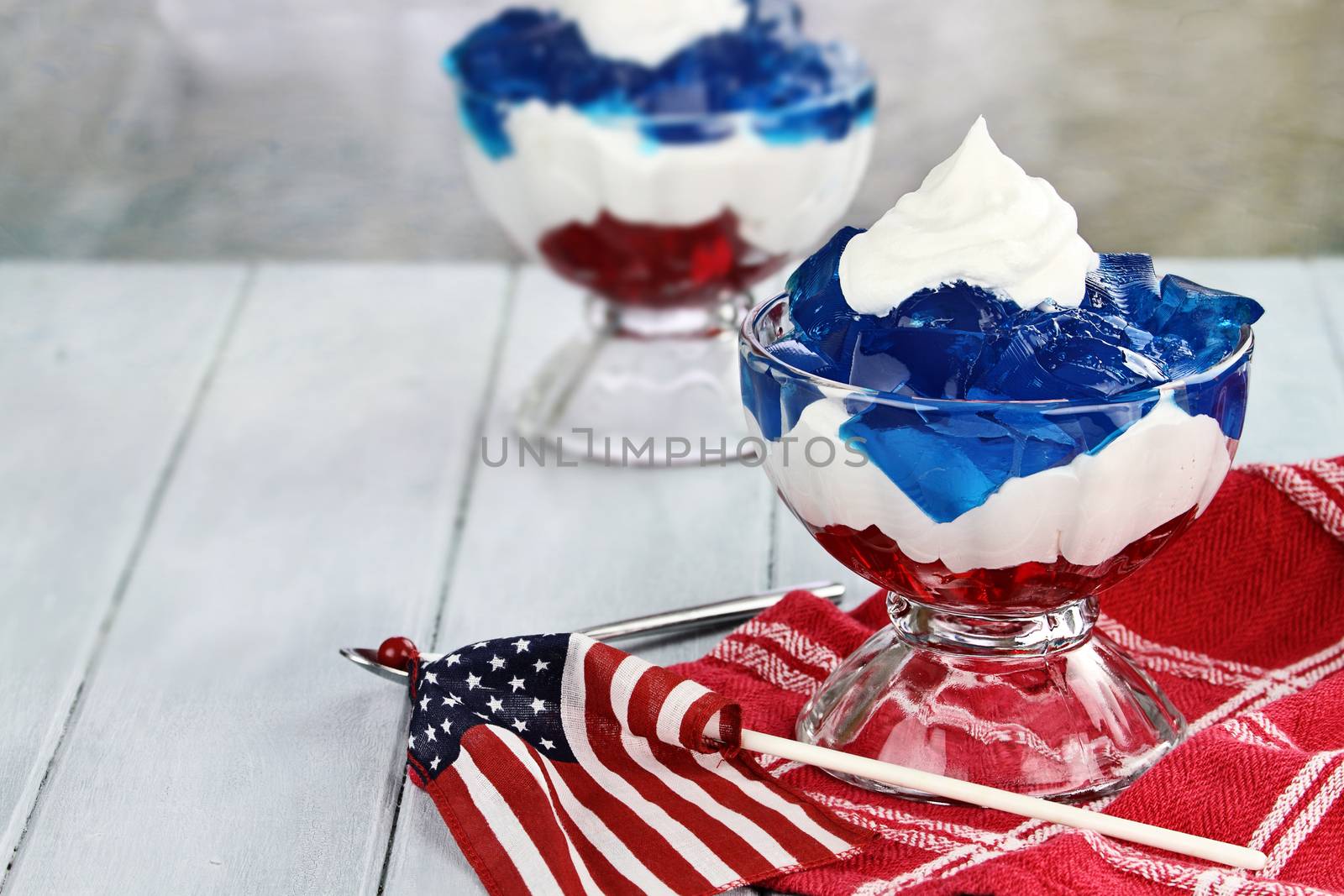 Gelatin layered dessert of cubes of red and blue jello with white fluffy whipped cream for the Fourth of July holiday. Shallow depth of field.