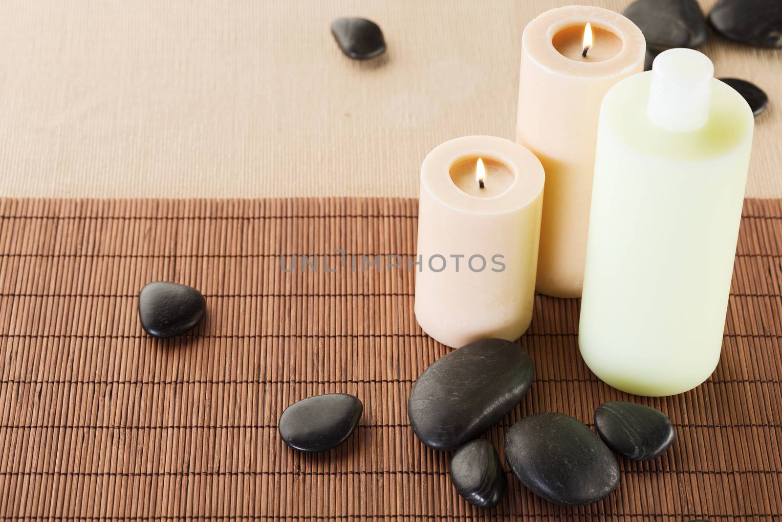 spa, health and beauty concept - closeup of shampoo bottle, massage stones and candles