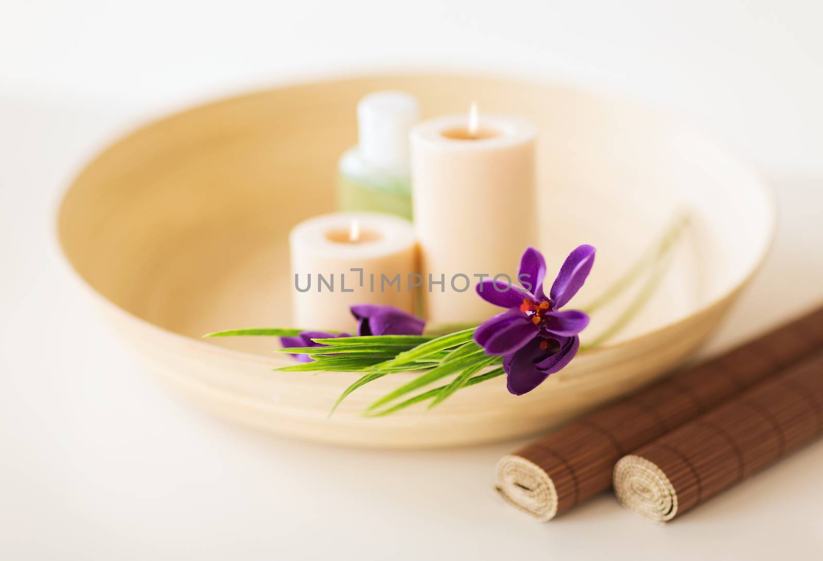 spa, health and beauty concept - candles and iris flowers in wooden bowl and bamboo mat