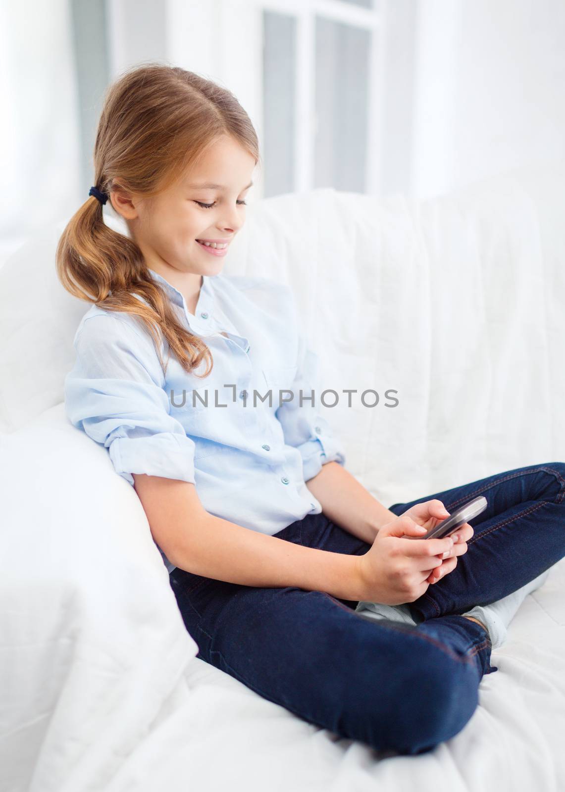 smiling girl with smartphone at home by dolgachov