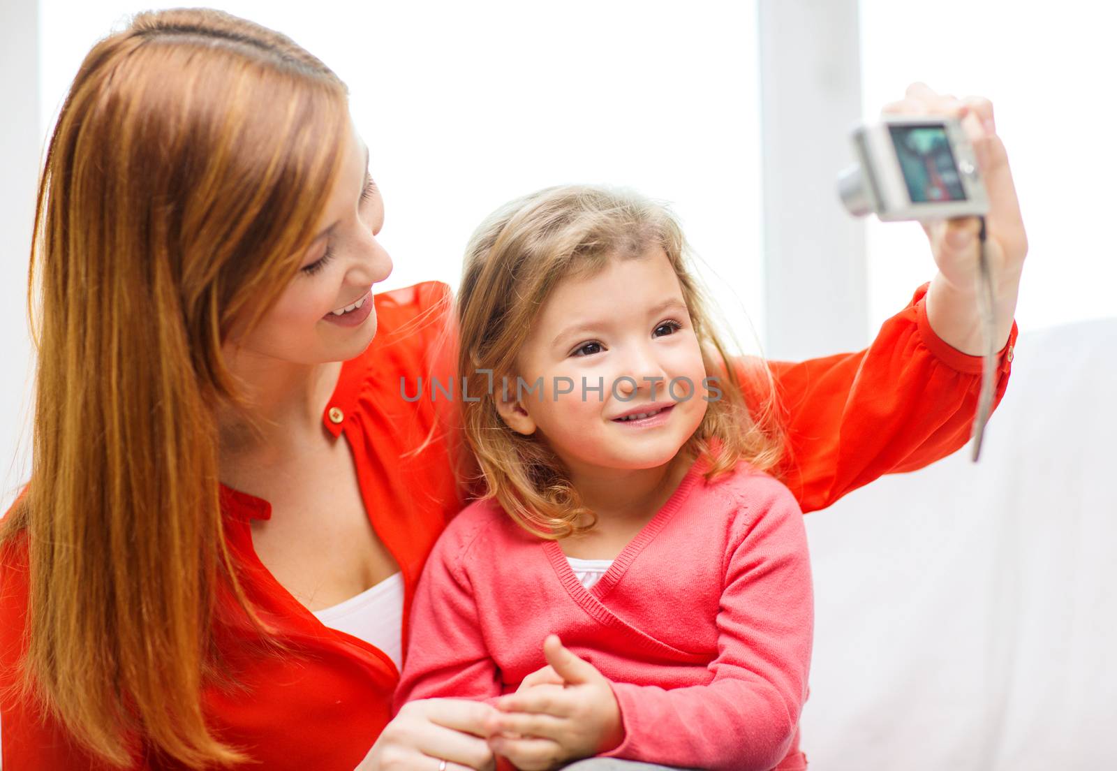 family, children, technology and happy people concept - smiling mother and daughter with digital camera