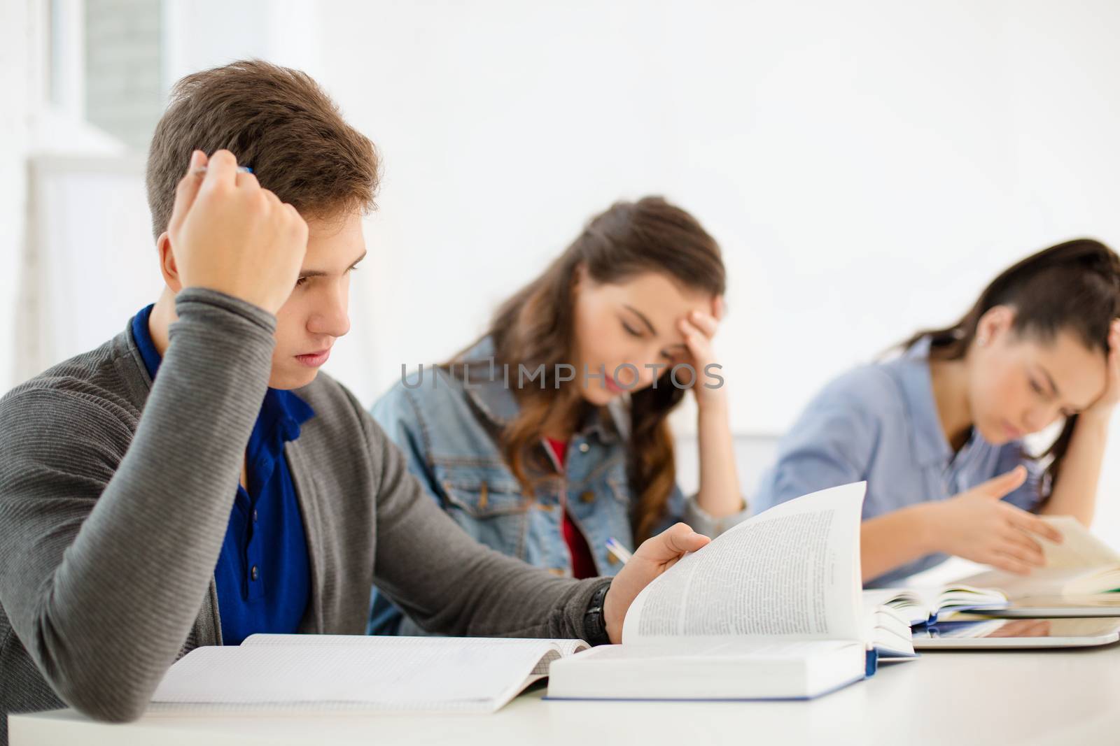 school and education concept - group of tired students with notebooks at school