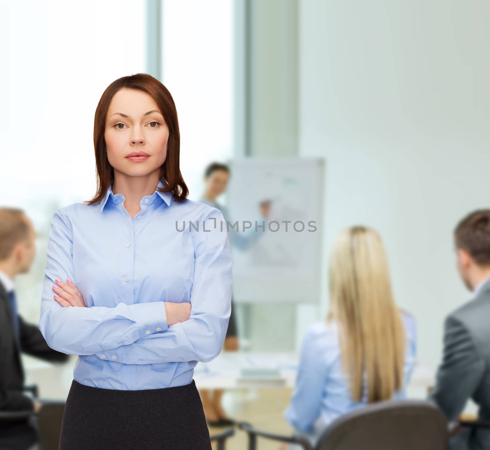 business and education concept - friendly young businesswoman with crossed arms at office