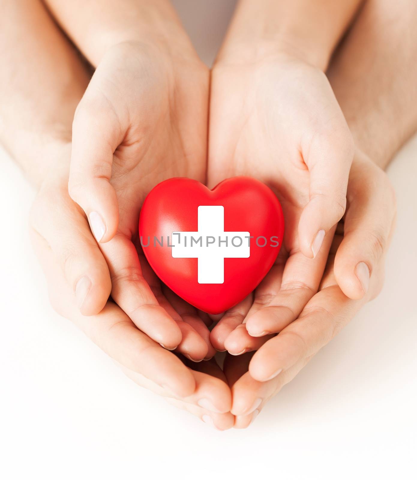 family health, charity and medicine concept - male and female hands holding red heart with cross sign