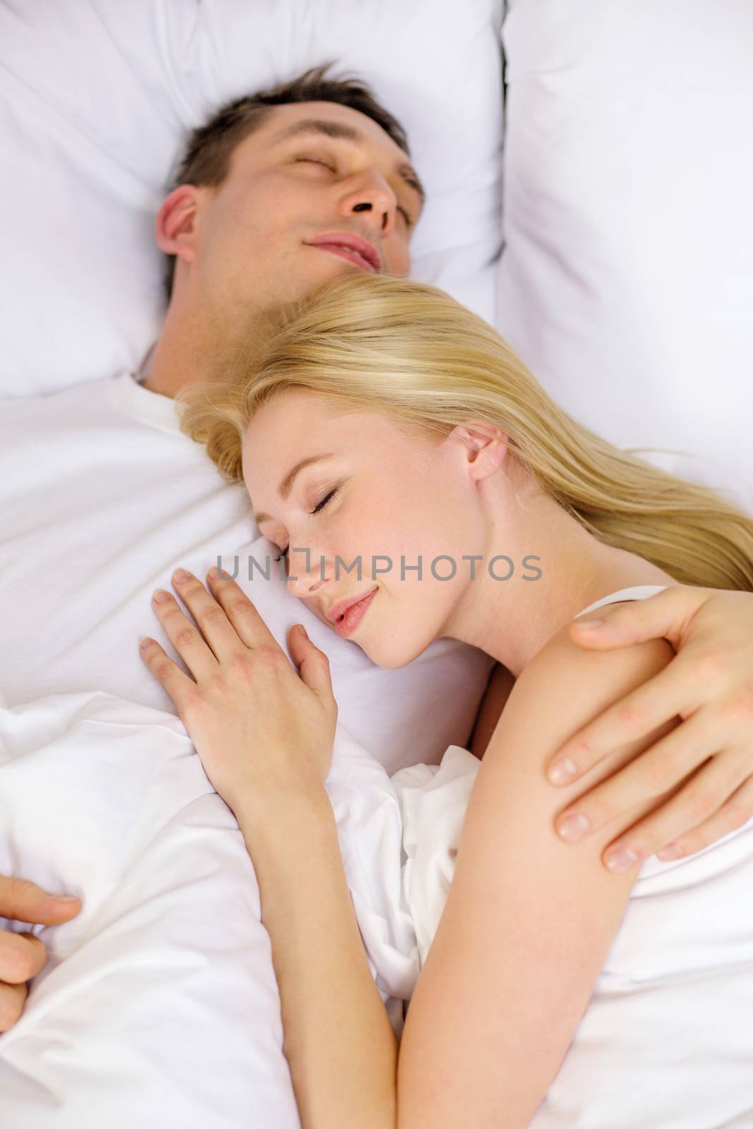 hotel, travel, relationships, and happiness concept - happy couple sleeping in bed