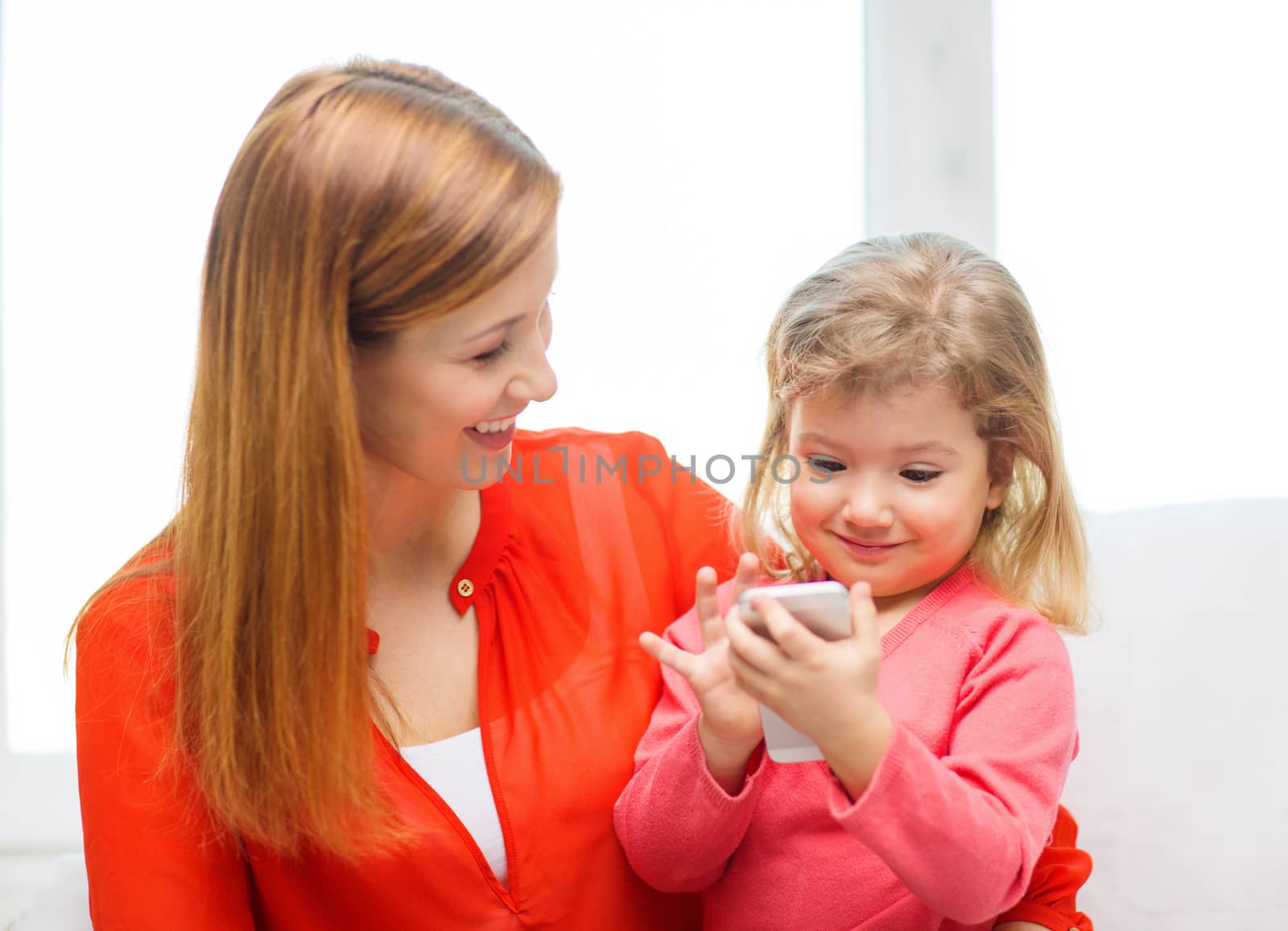 happy mother and daughter with smartphone at home by dolgachov