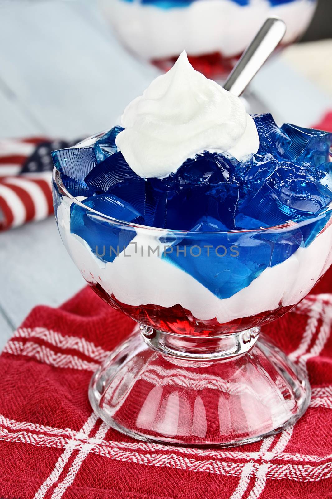 Gelatin layered dessert of cubes of red and blue jello with white fluffy whipped cream for the Fourth of July holiday. Shallow depth of field.