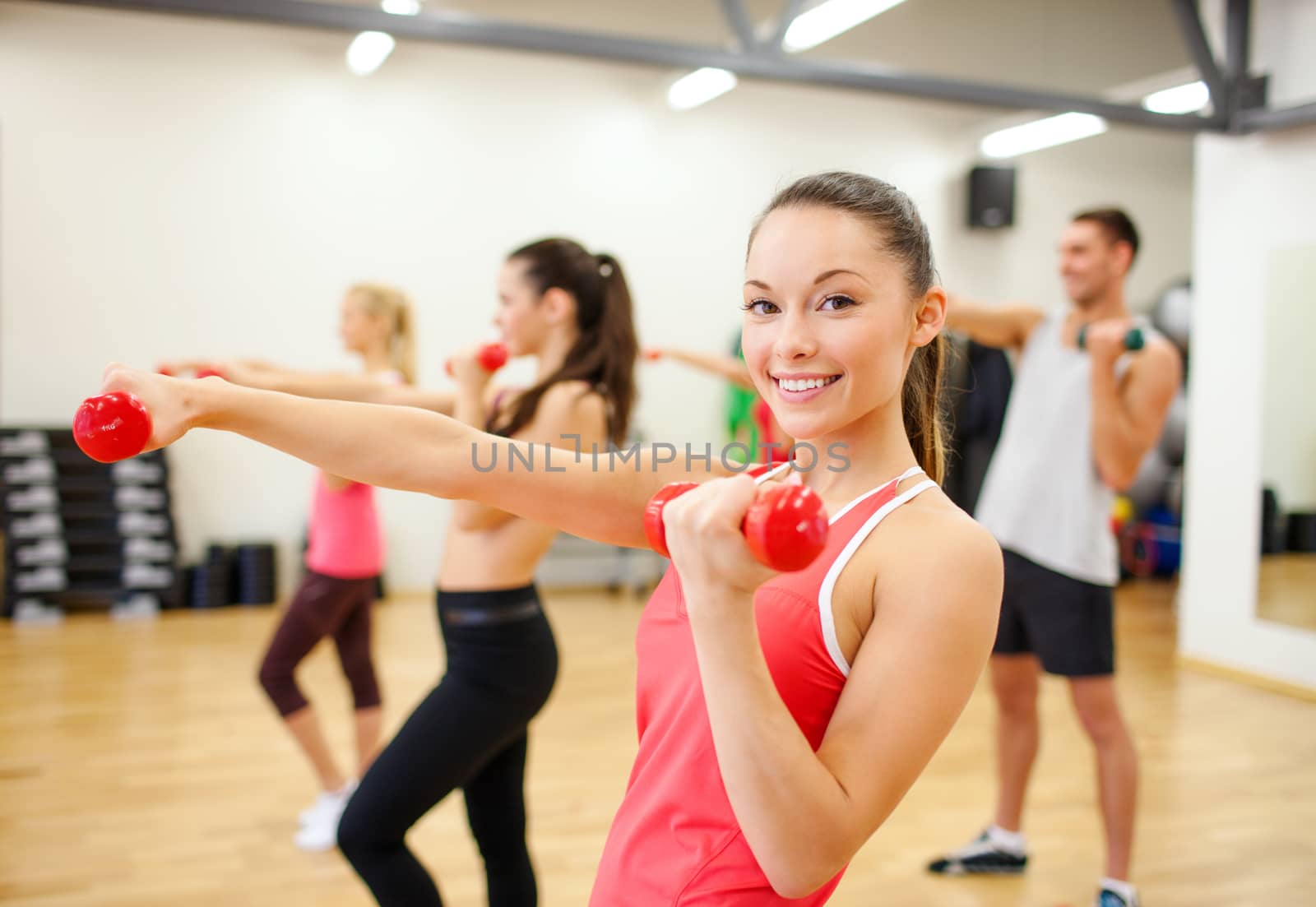 fitness, sport, training, gym and lifestyle concept - group of smiling people working out with dumbbells in the gym