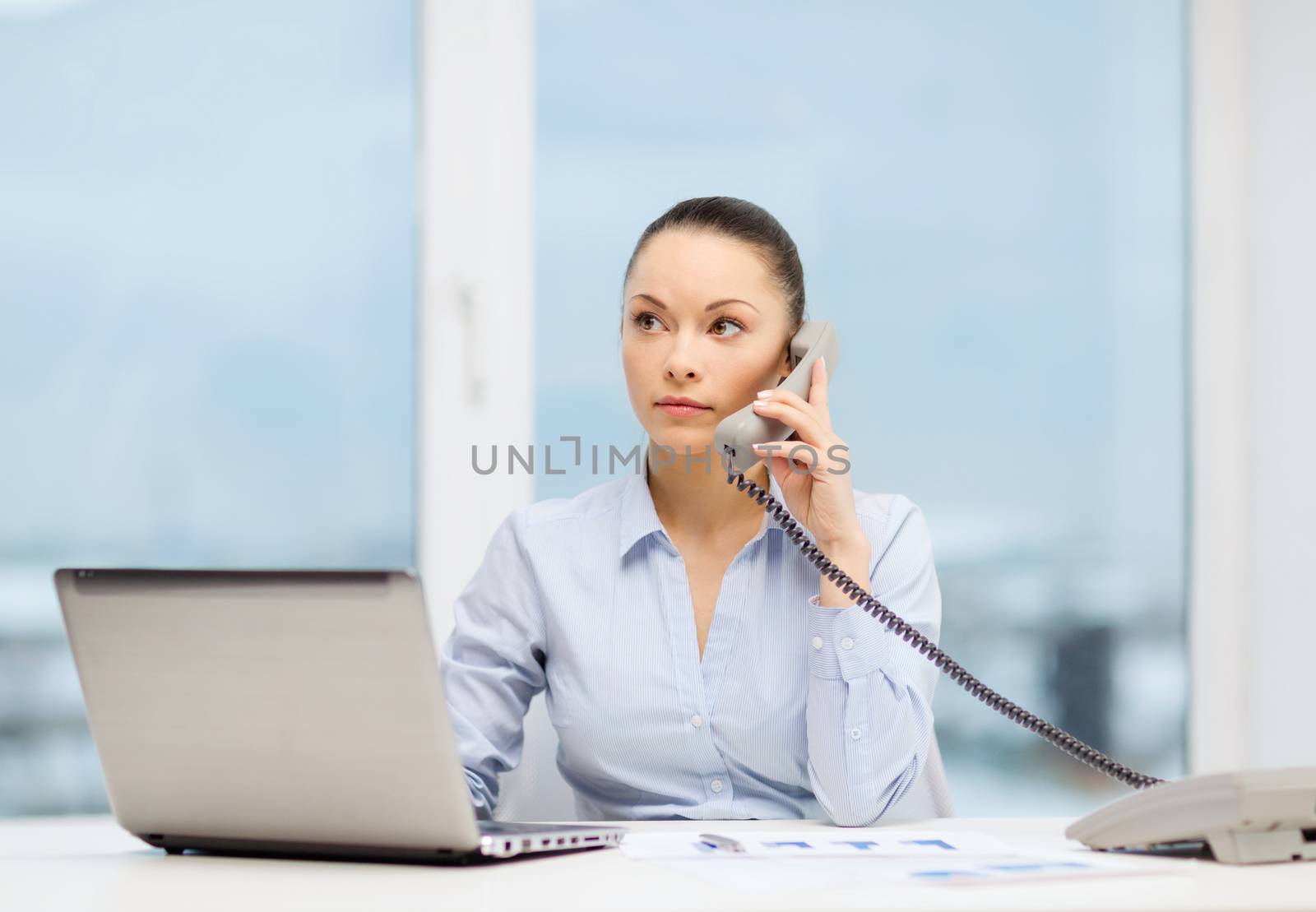 business, technology and communication concept - smiling businesswoman with phone, laptop and files in office