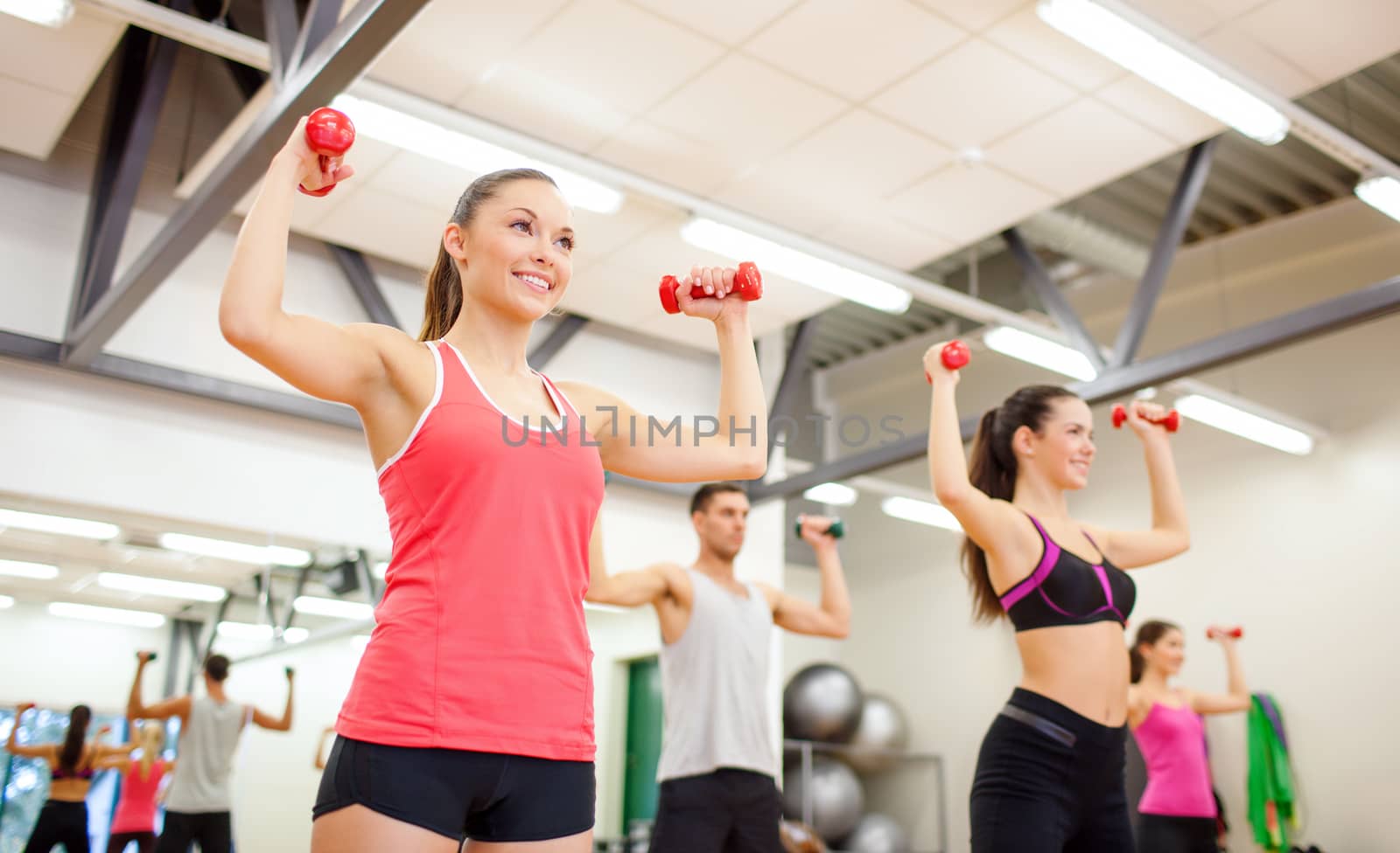 fitness, sport, training, gym and lifestyle concept - group of smiling people working out with dumbbells in the gym