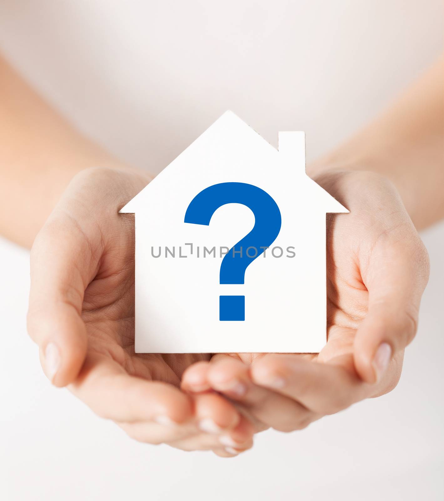 real estate and family home concept - hands holding paper house with question mark
