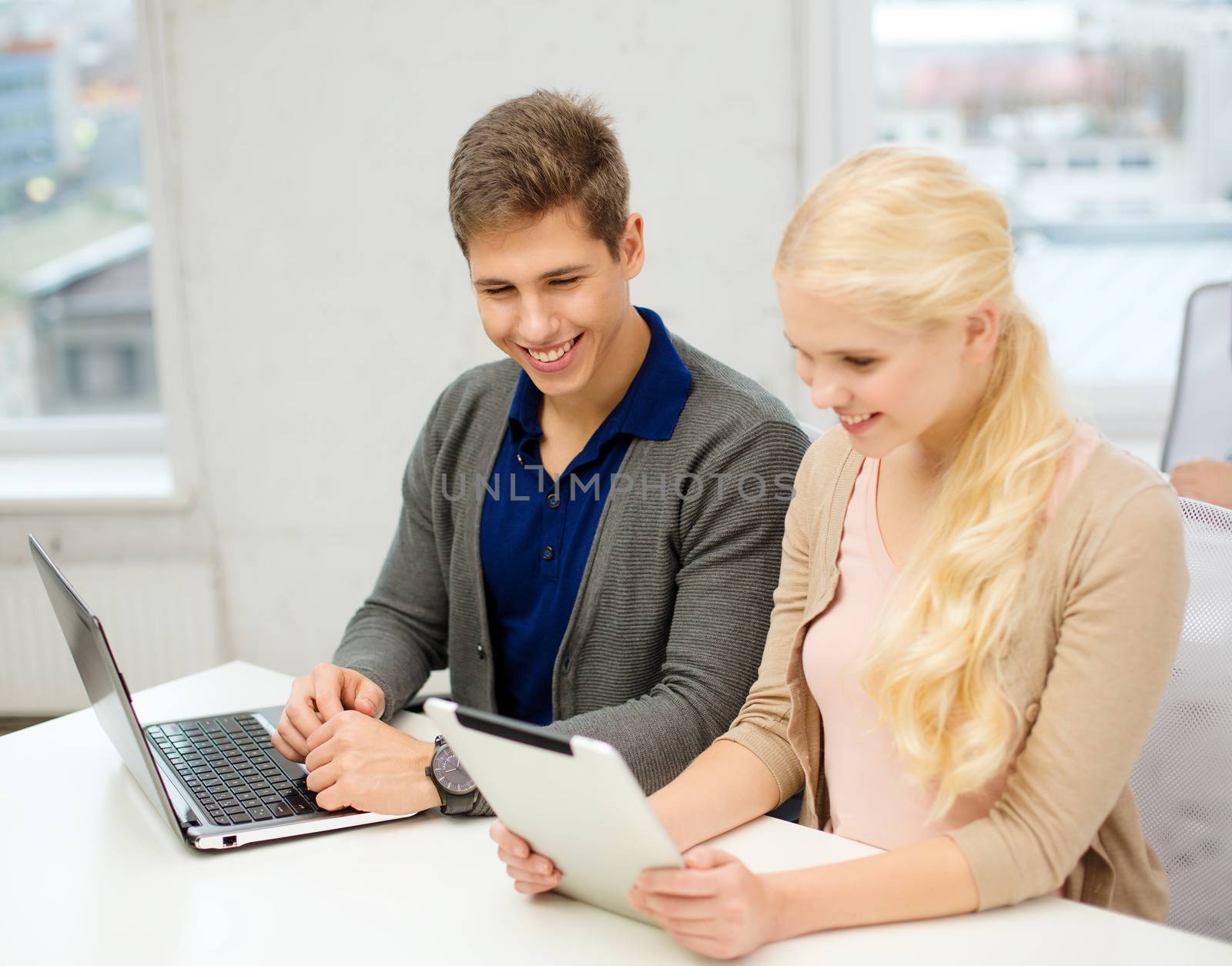 school, education, technology and internet concept - two teens with laptop and tablet pc at school