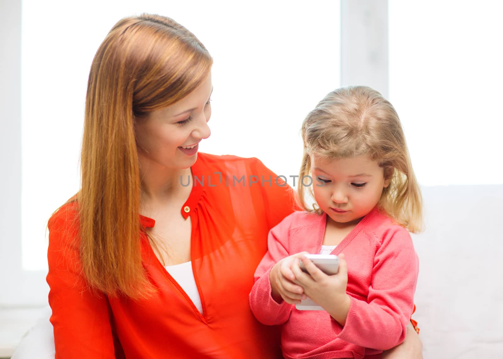 happy mother and daughter with smartphone at home by dolgachov