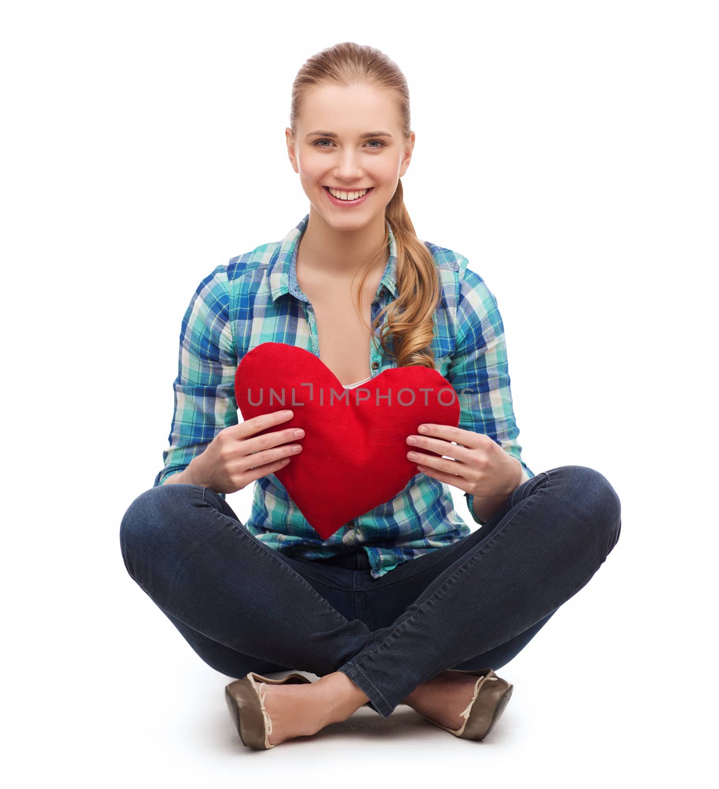 happiness and people concept - smiling young woman in casual clothes sitiing on floor and holding red heart