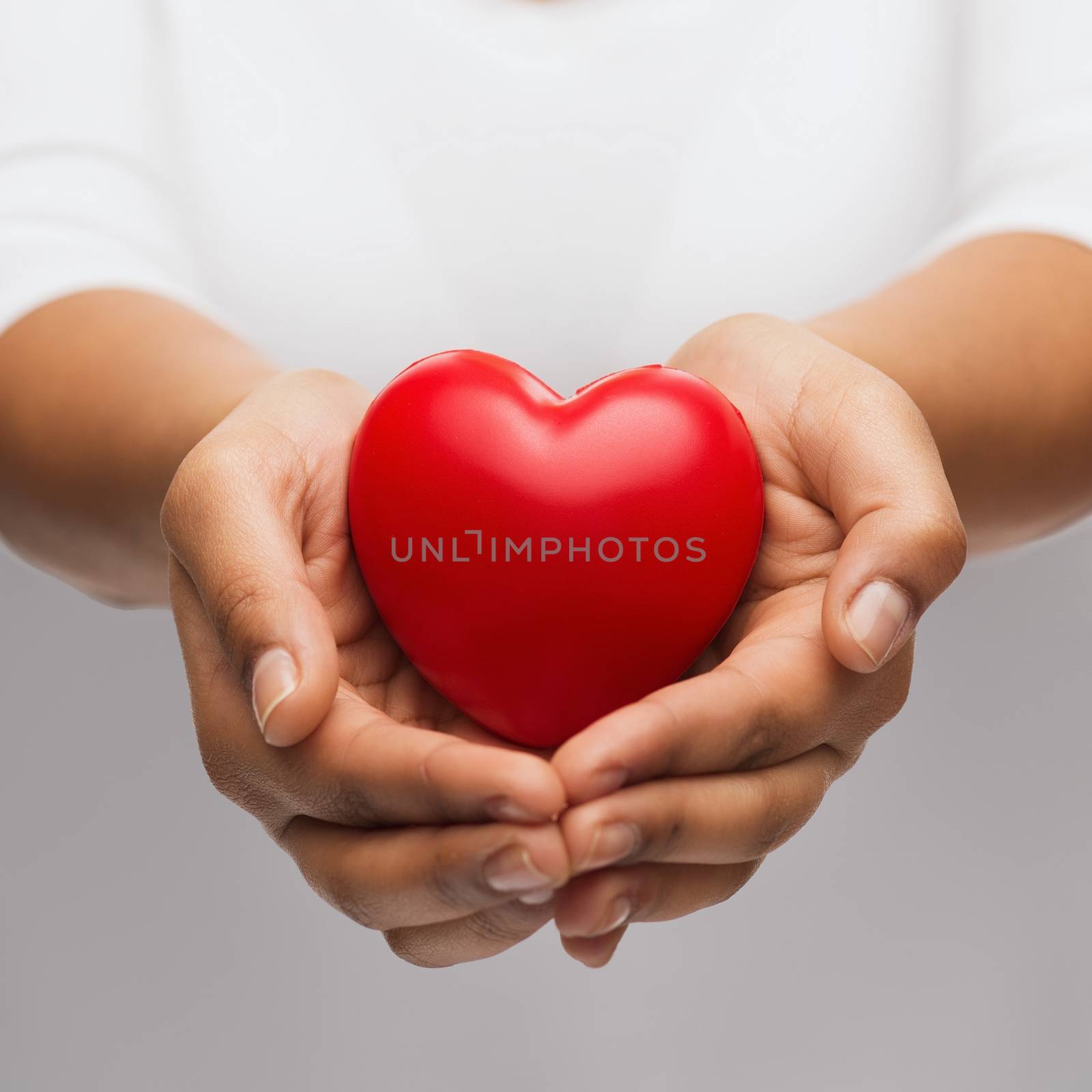 people, relationship and love concept - close up of womans cupped hands showing red heart