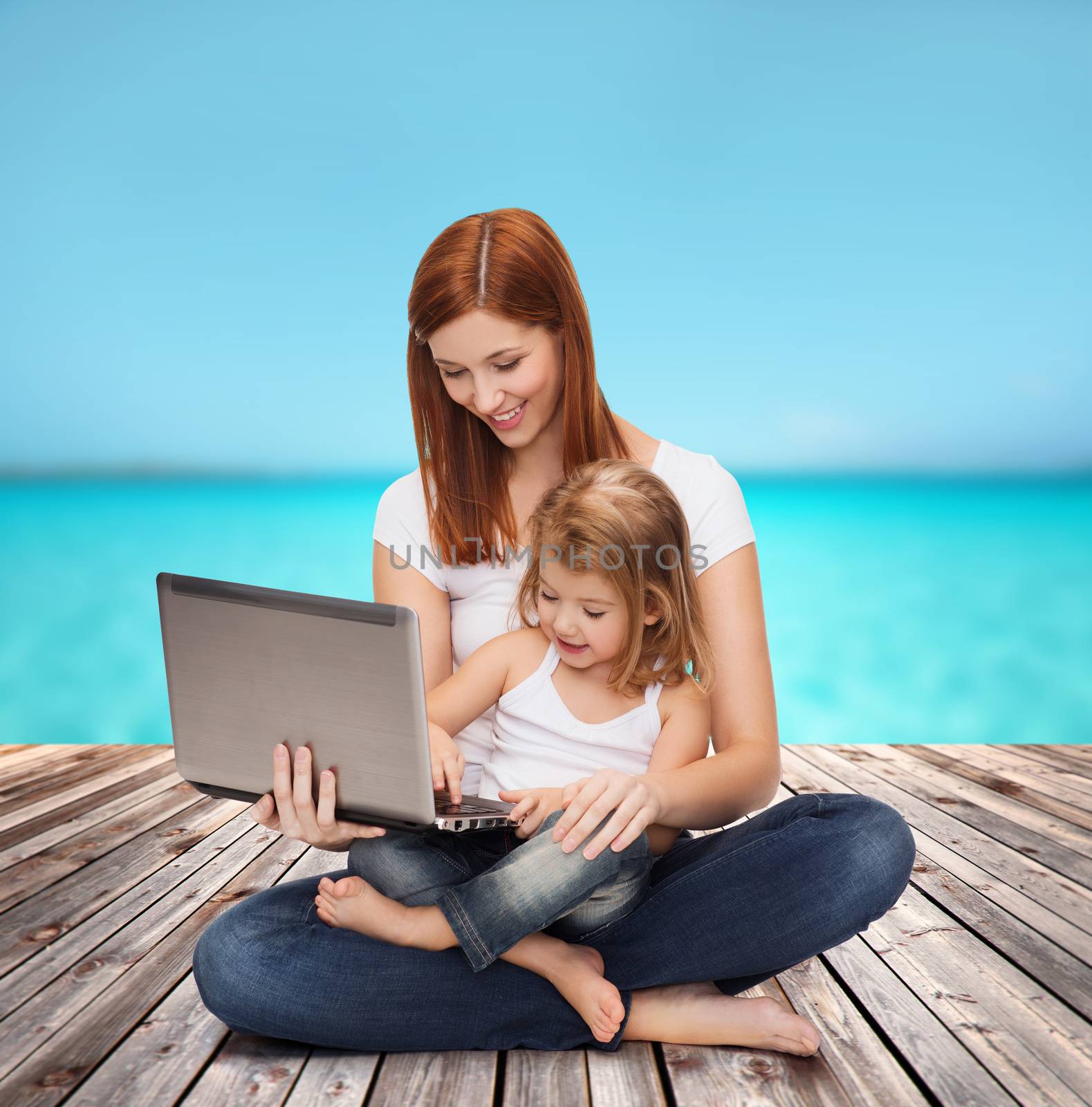 childhood, parenting and technology concept - happy mother with adorable little girl with laptop