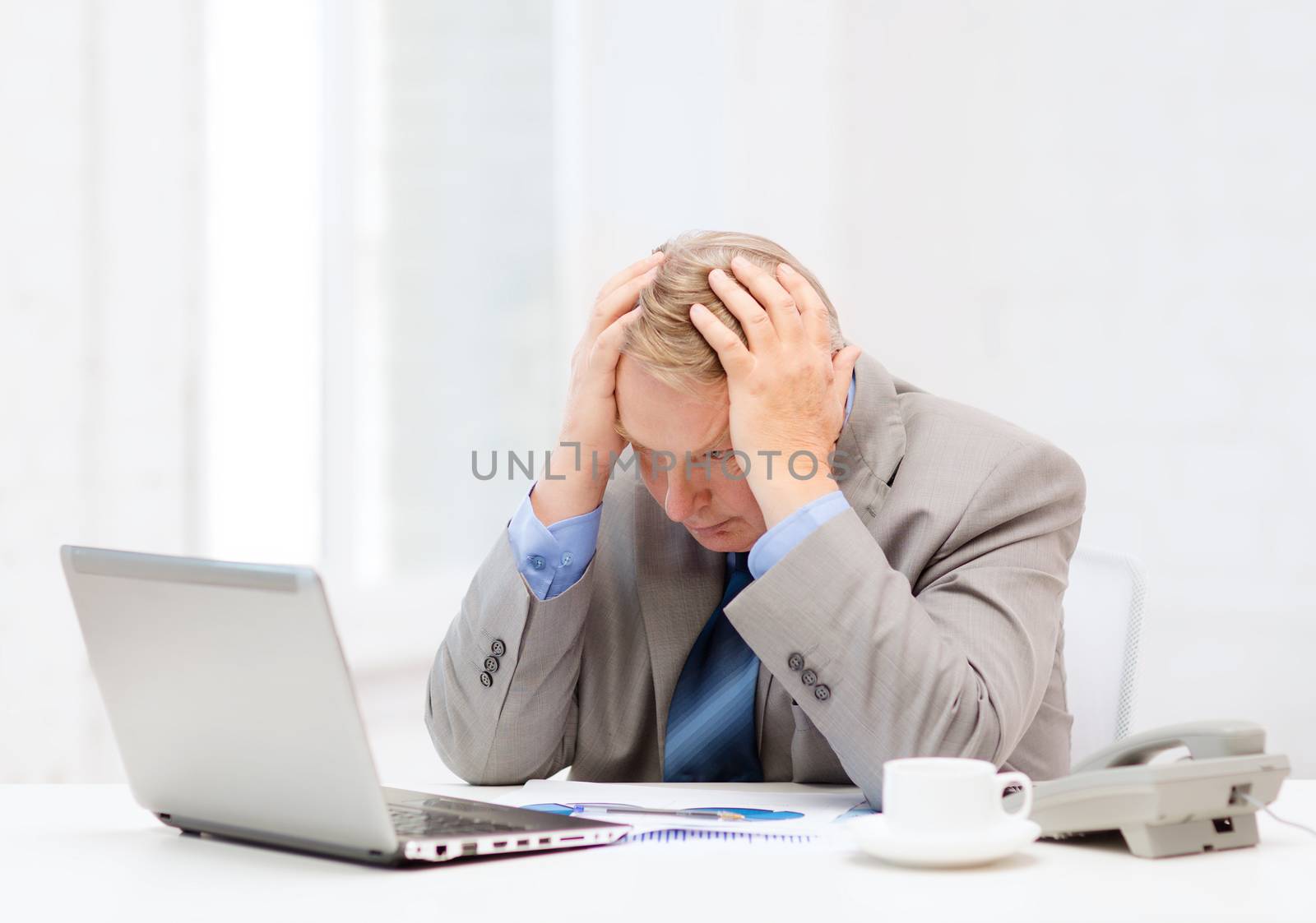 upset older businessman with laptop and telephone by dolgachov
