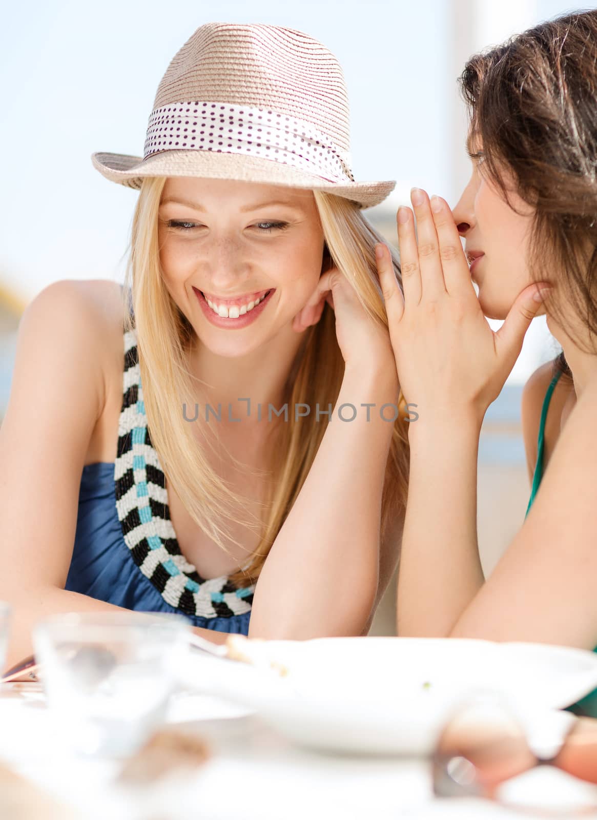 summer holidays and vacation concept - girls gossiping in cafe on the beach