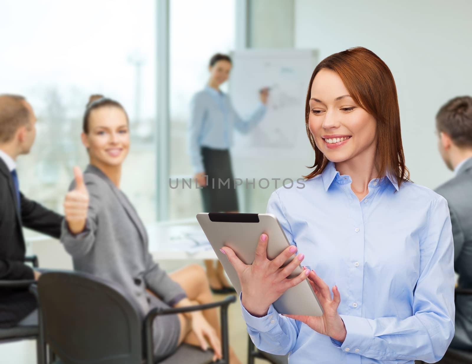 smiling woman looking at tablet pc at office by dolgachov