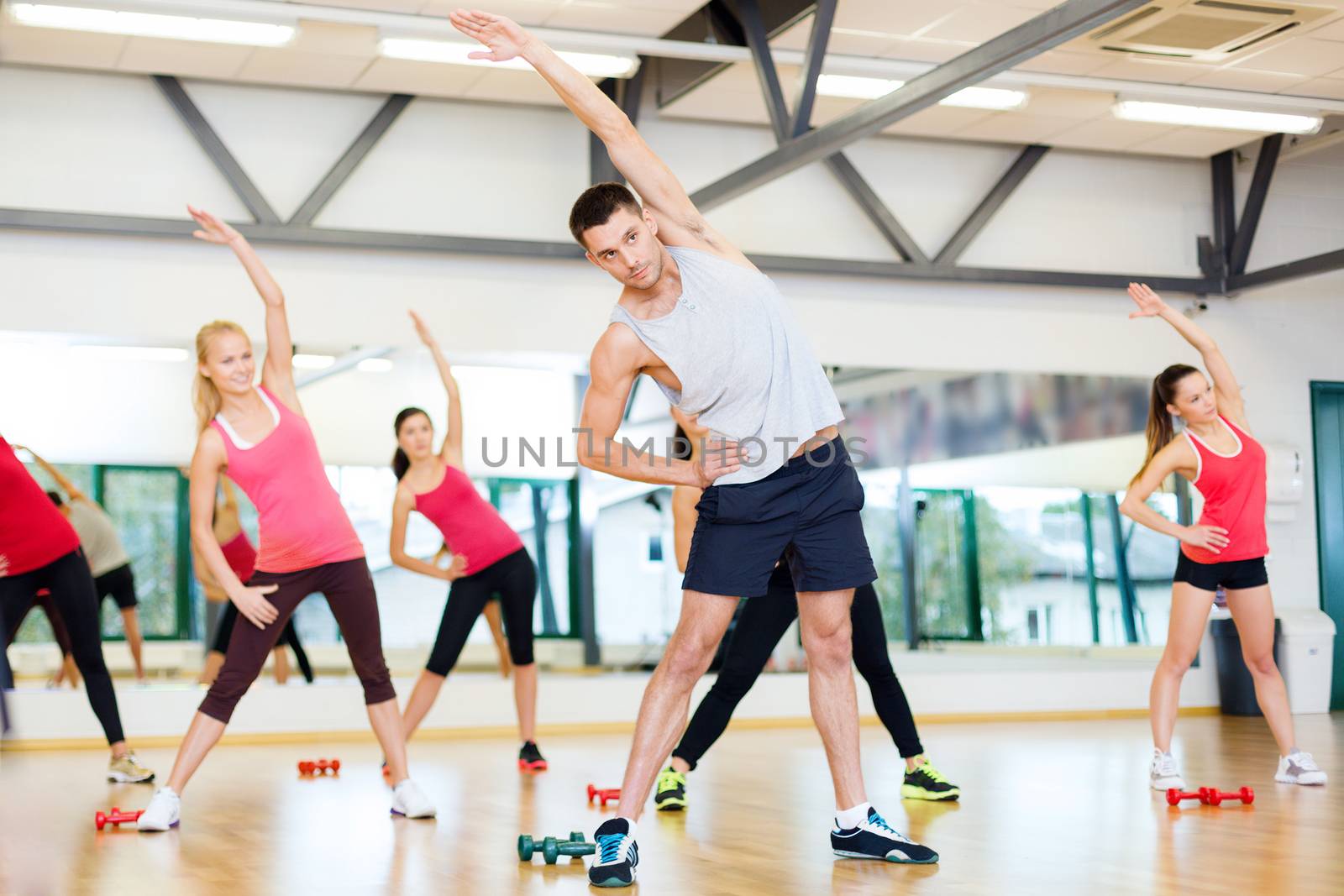 fitness, sport, training, gym and lifestyle concept - group of smiling women stretching in the gym