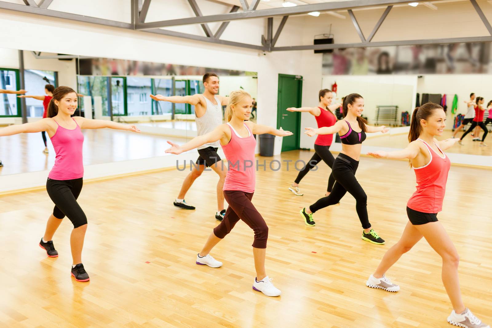 group of smiling people exercising in the gym by dolgachov