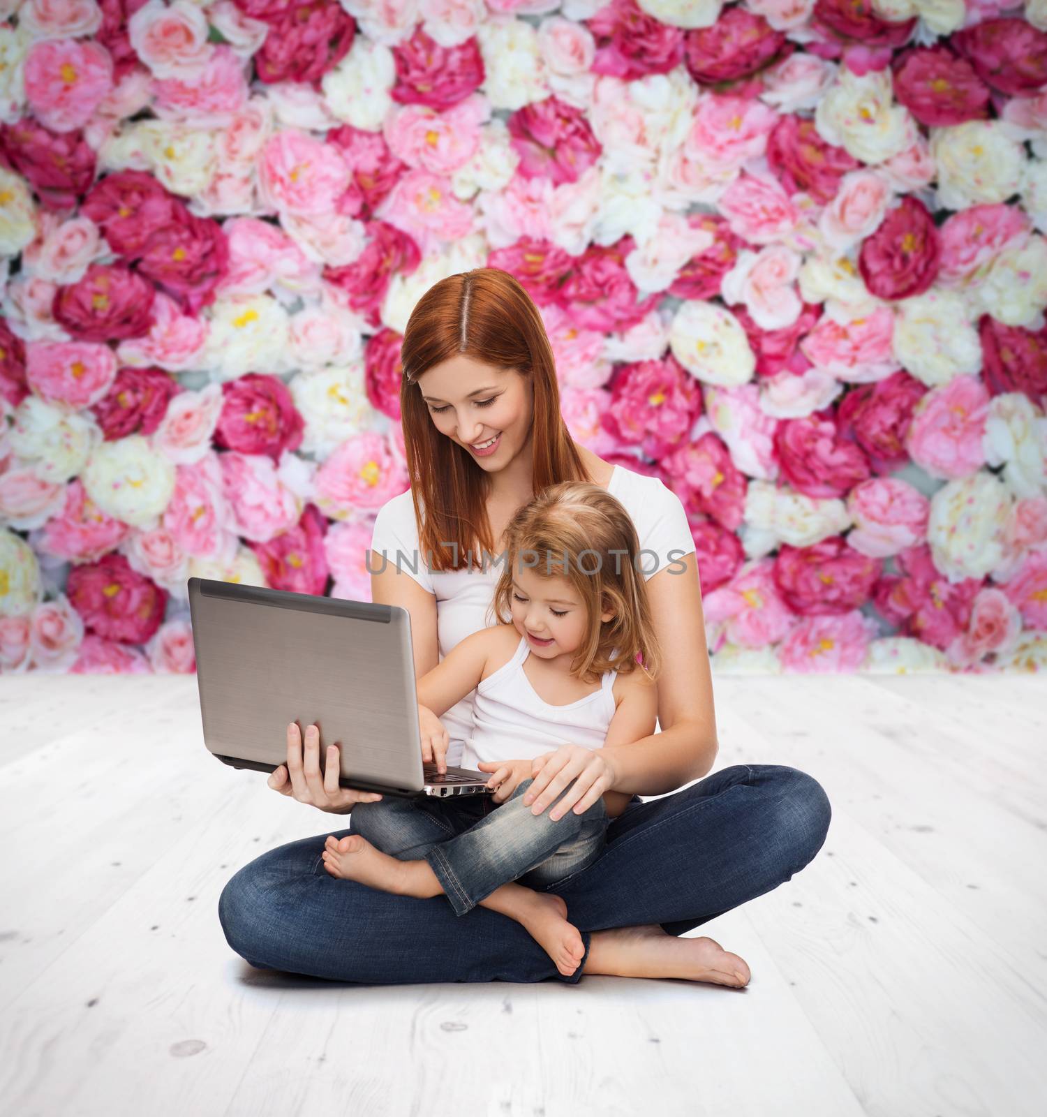 childhood, parenting and technology concept - happy mother with adorable little girl with laptop