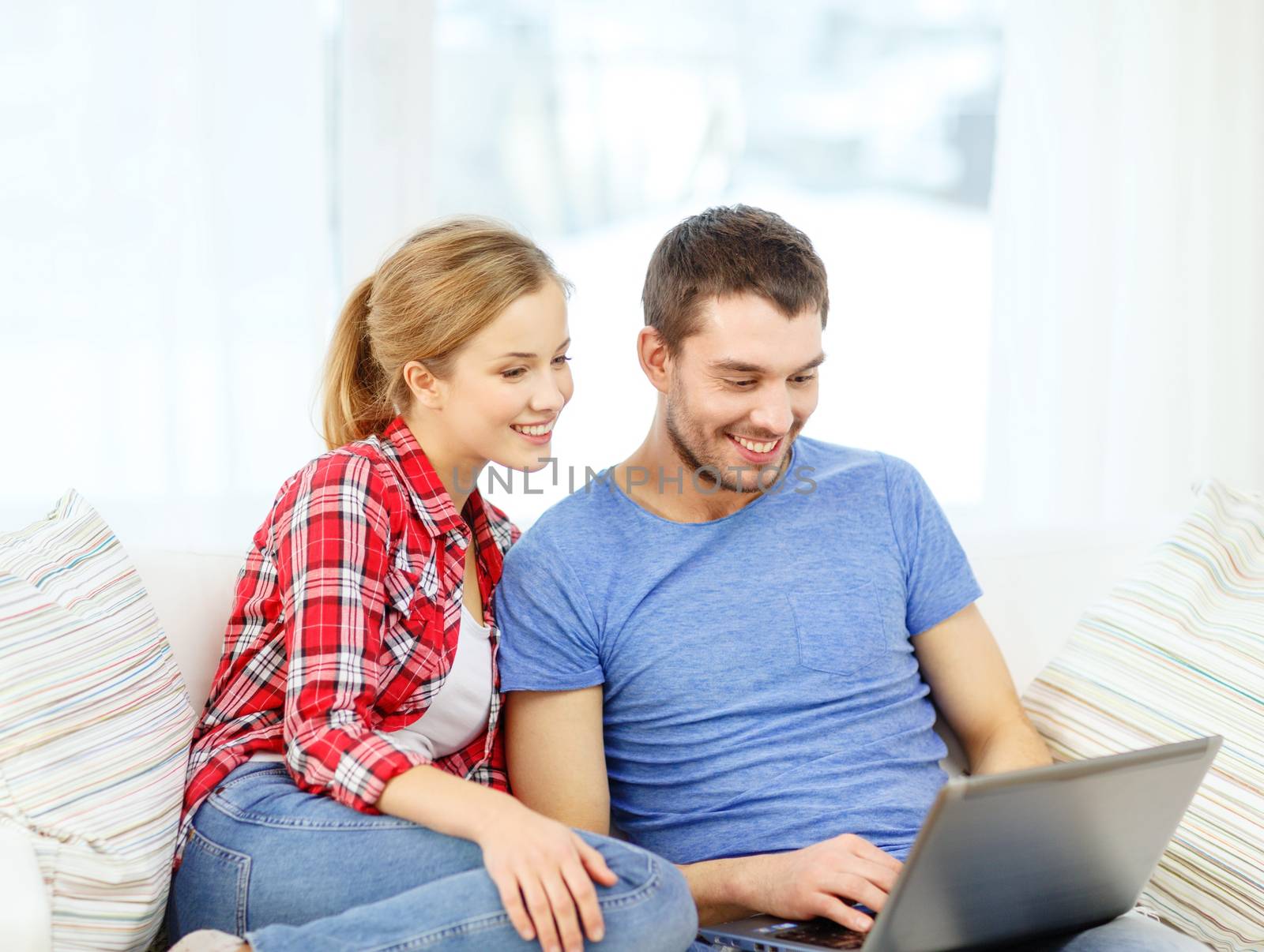 home, technology and relationships concept - smiling couple with laptop computer at home