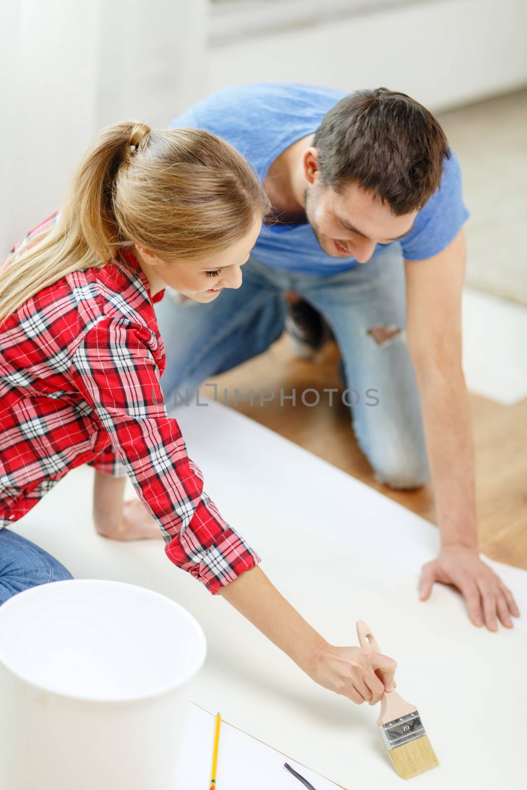 smiling couple smearing wallpaper with glue by dolgachov