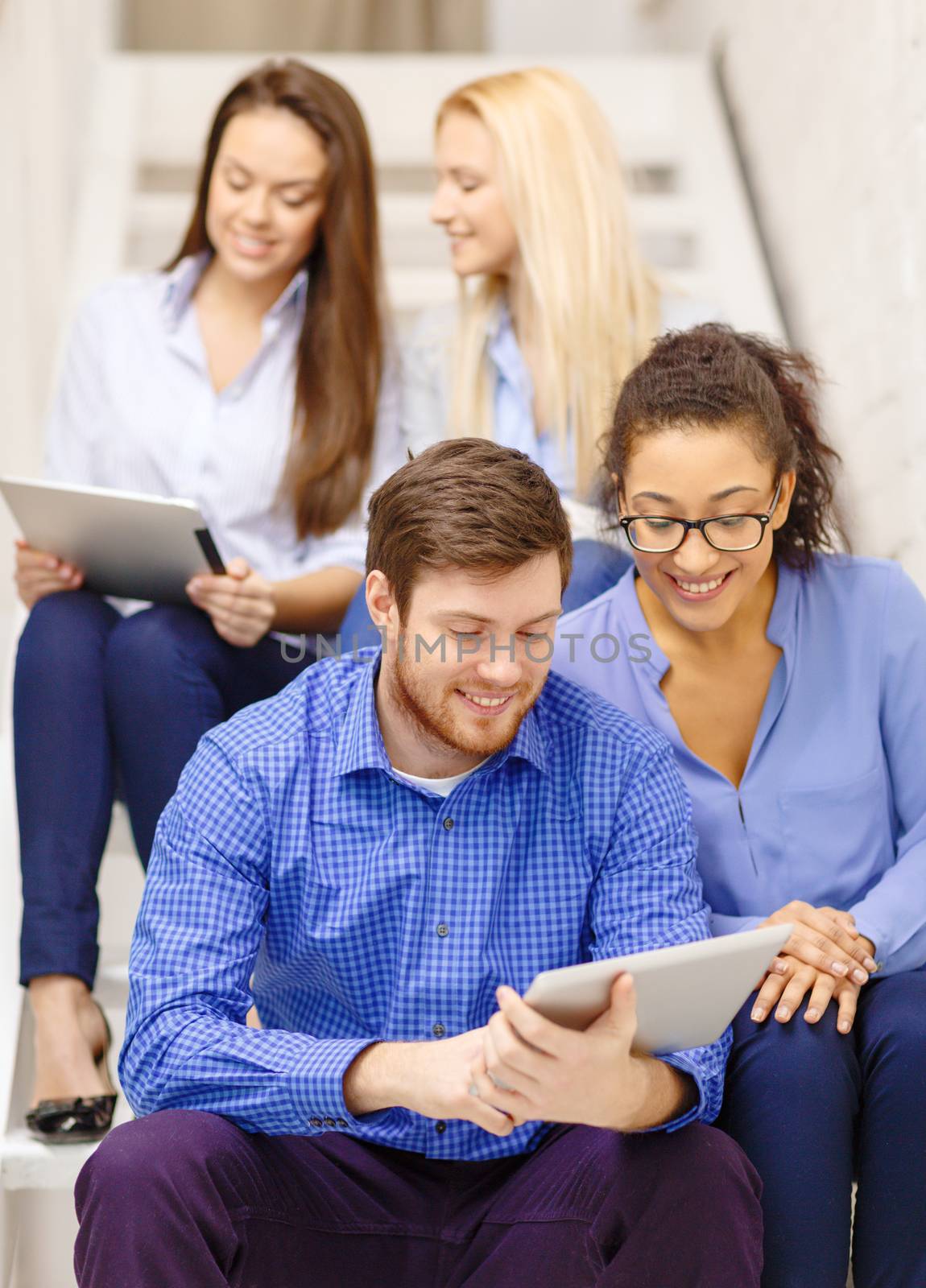 team with tablet pc computer sitting on staircase by dolgachov