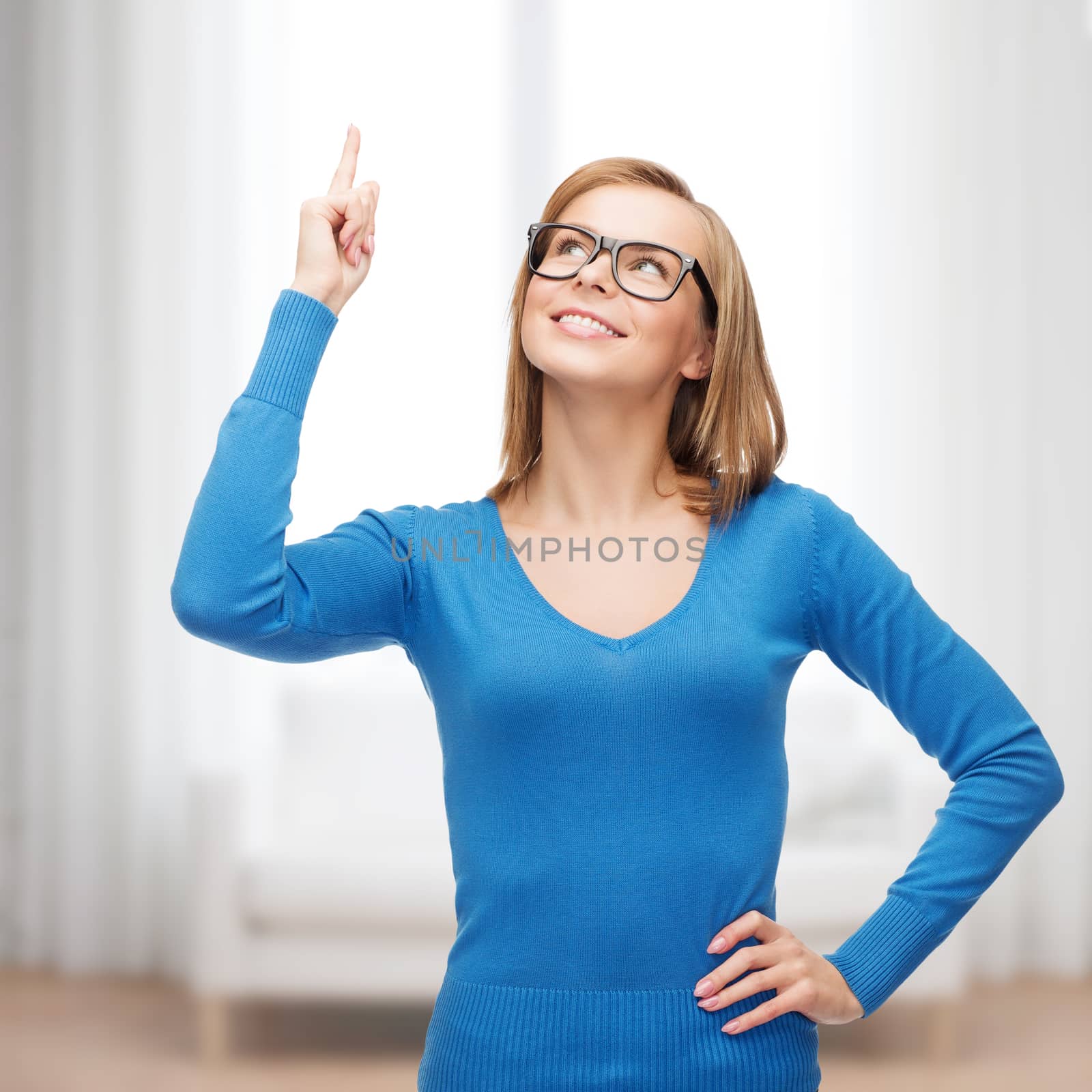 advertisement concept - attractive young woman in casual clothes and black eyeglasses pointing her finger up