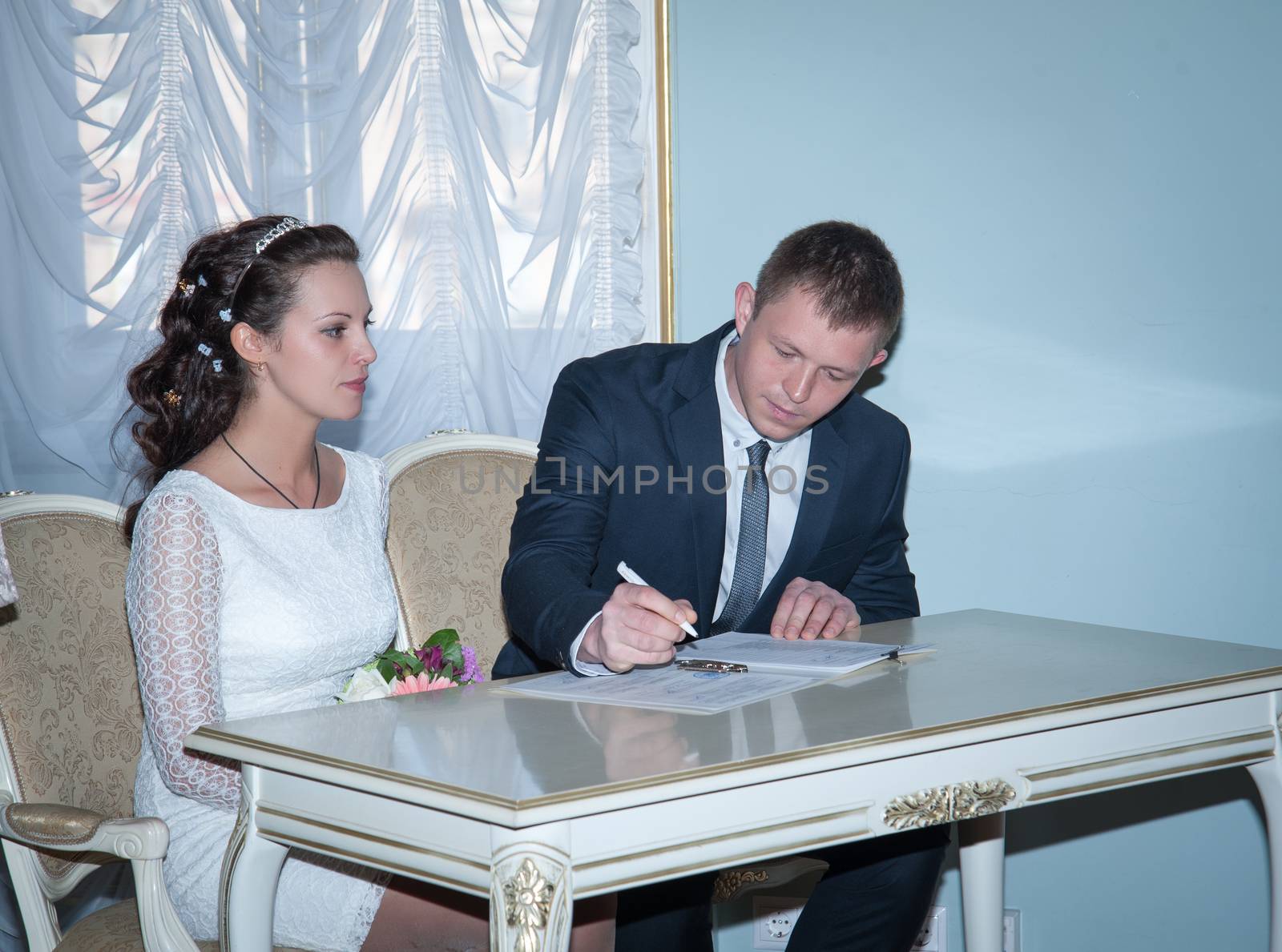 groom puts his signature under the marriage registration