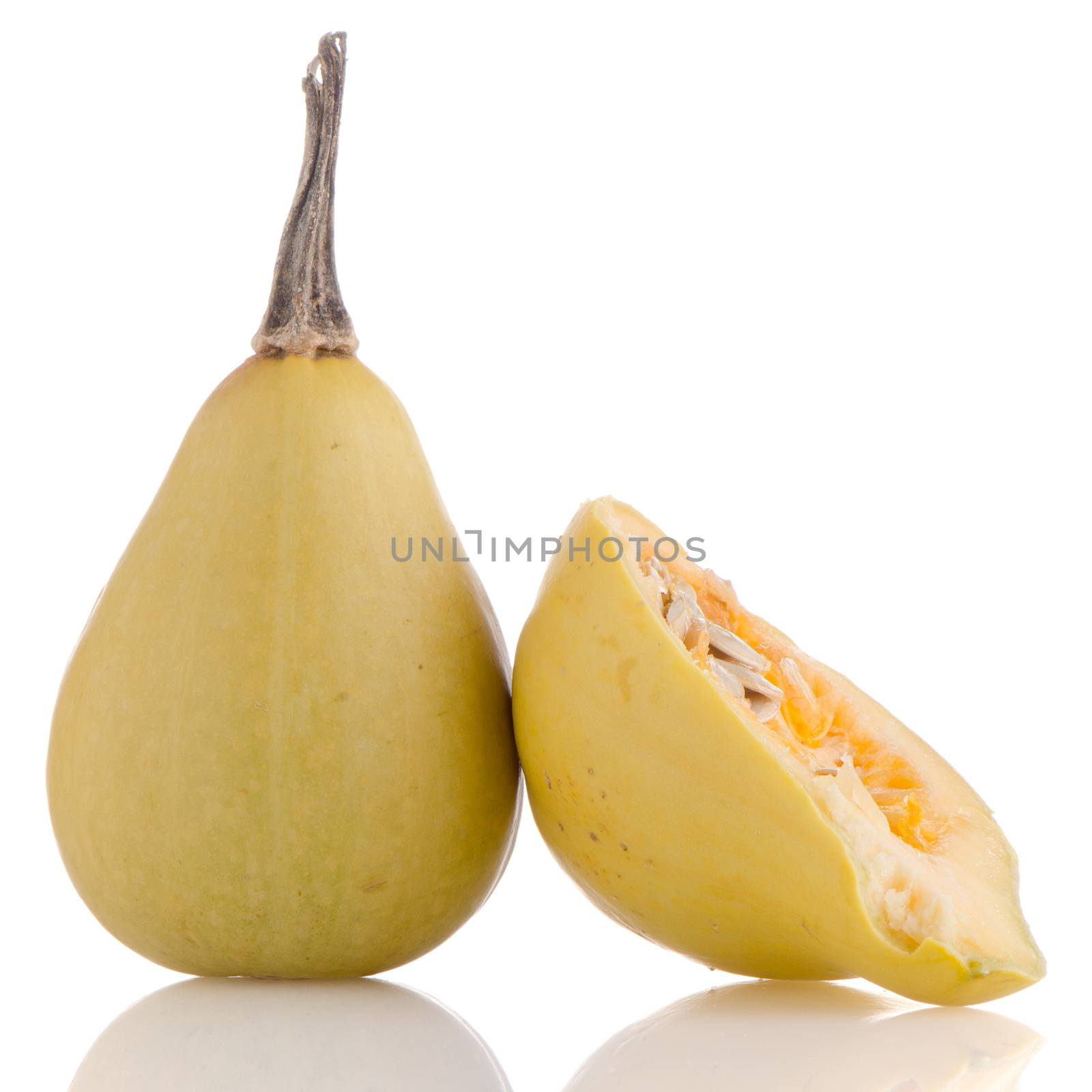 Closeup detail of yellow pumpkin on white reflective background.