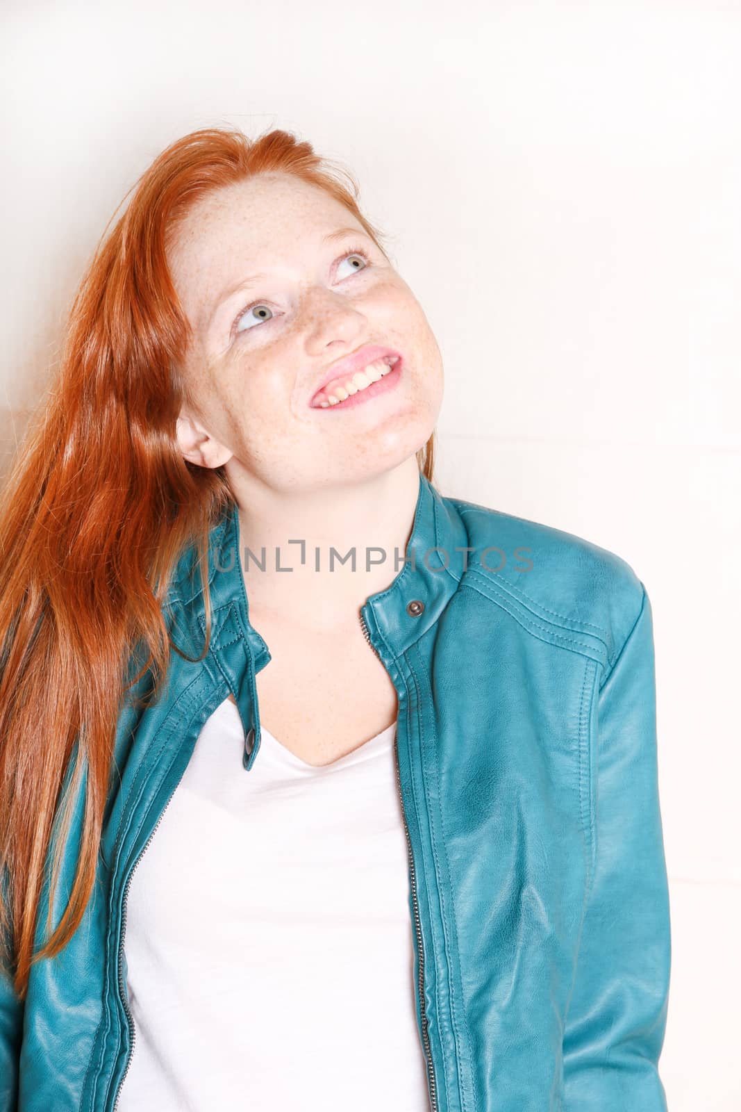 A attractive young, redhead woman with a green jacket.  
