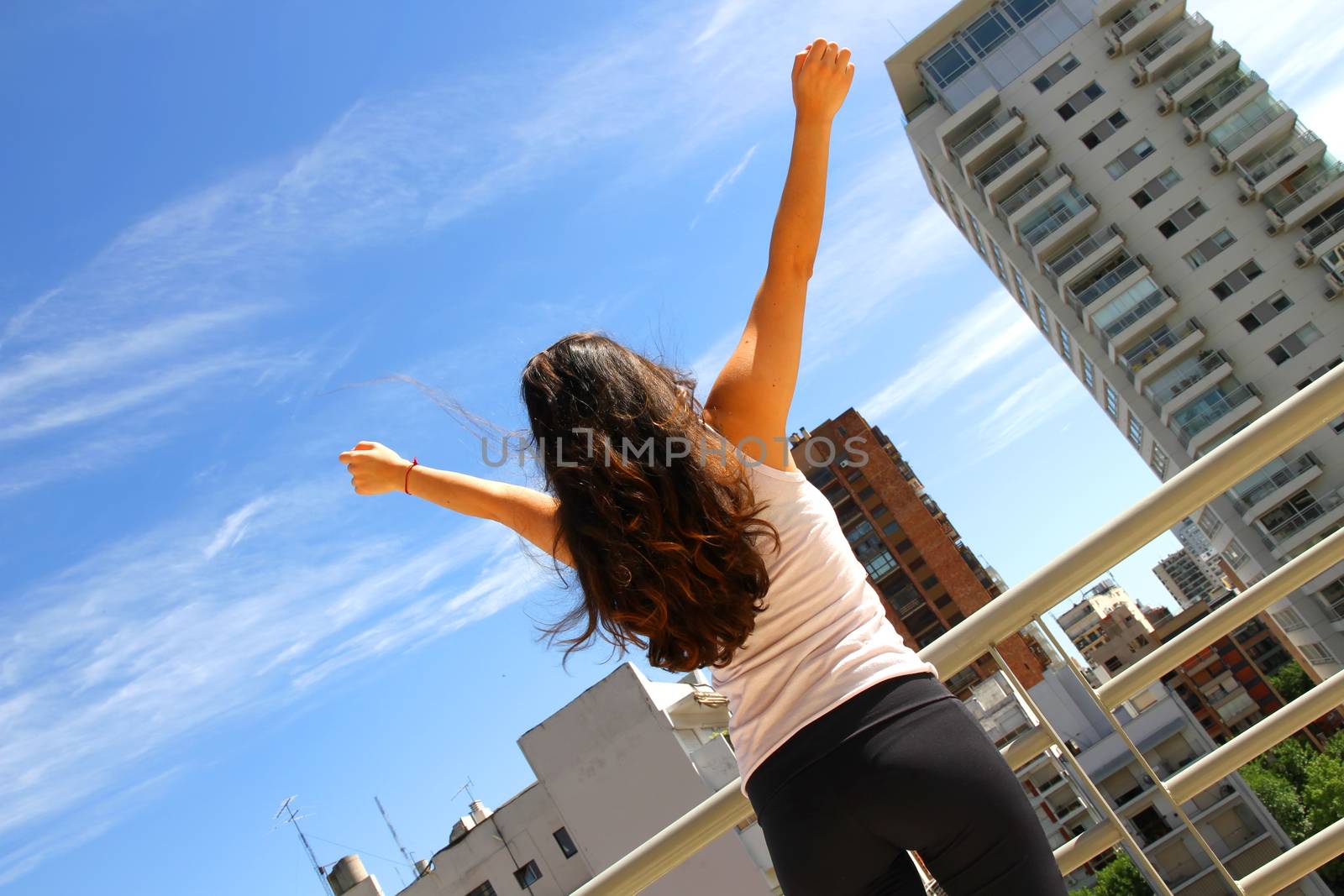 A young adult woman practicing Yoga in an urban environment.