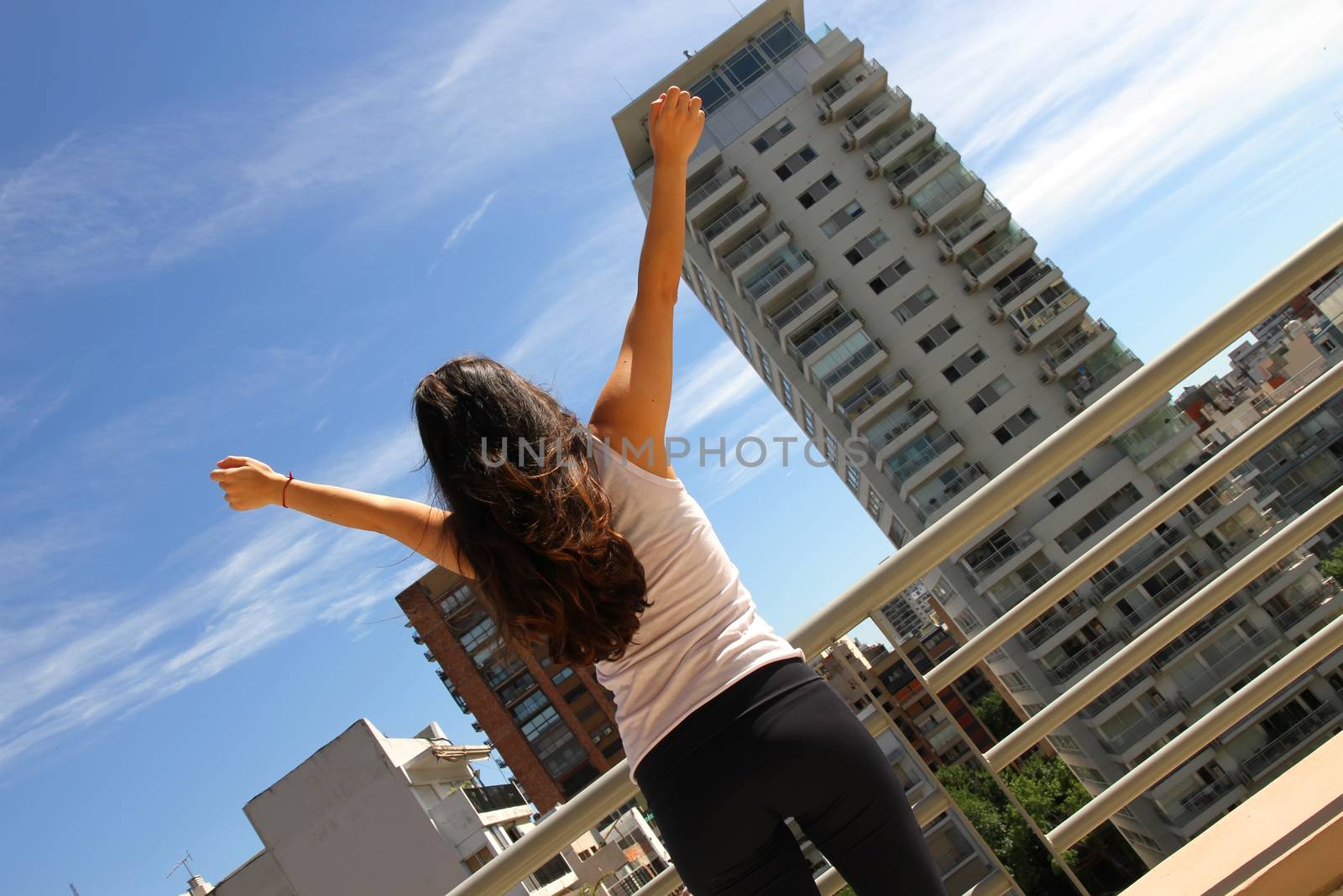 A young adult woman practicing Yoga in an urban environment.