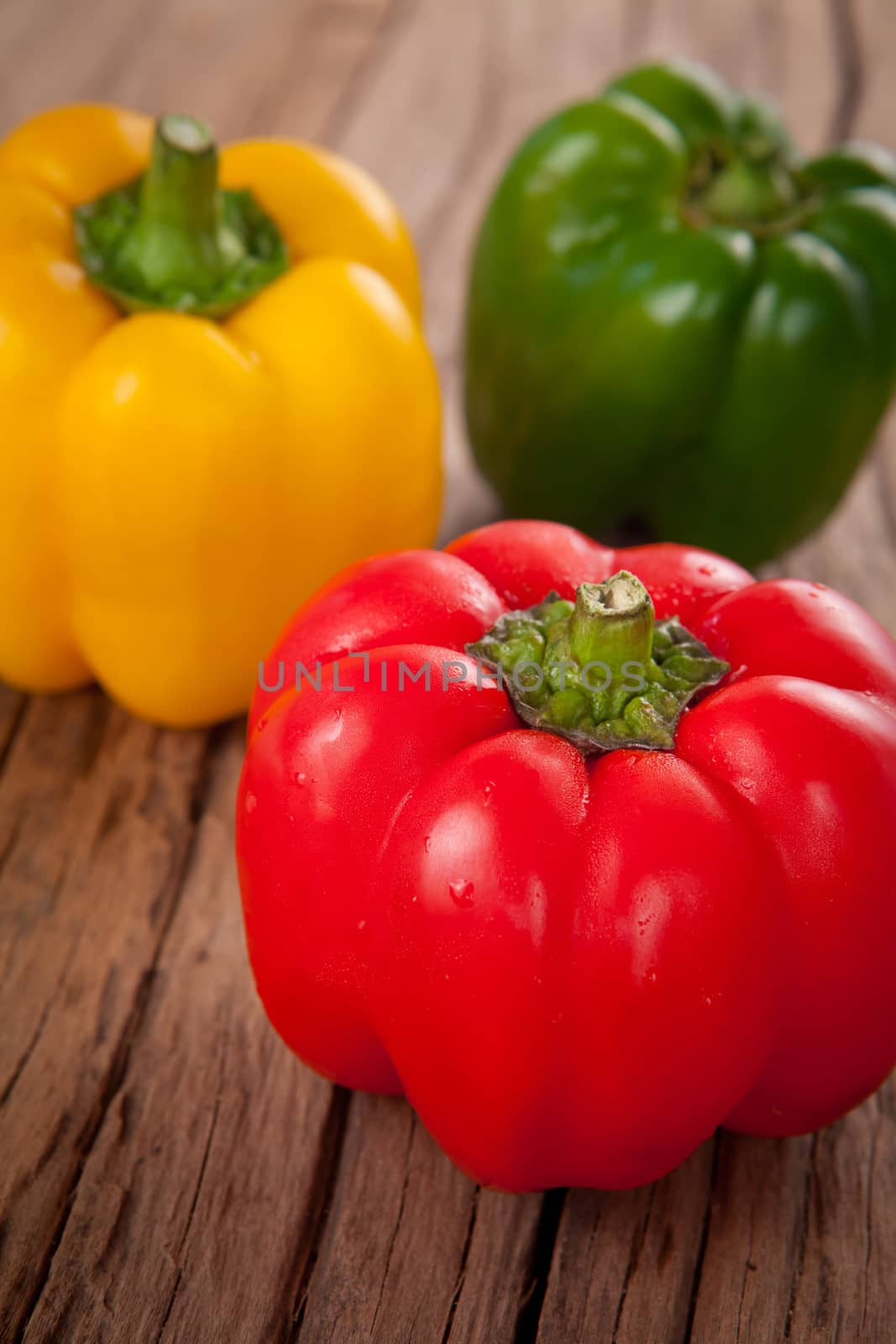 three sweet peppers, wooden table background