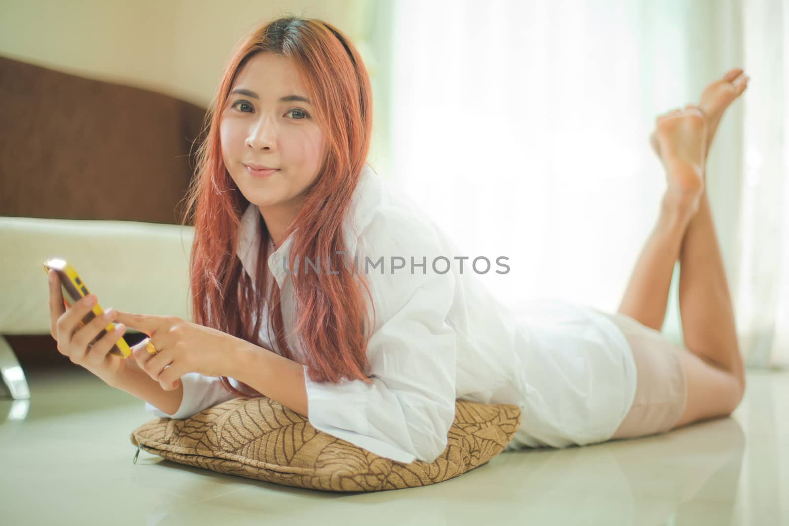 Happy asian young woman lying using smart phone at home