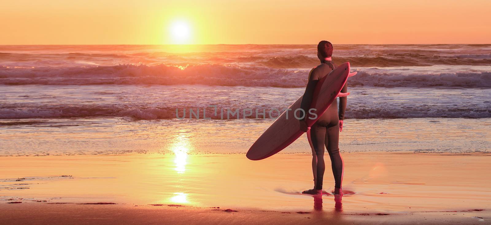 Surfer watching the waves at sunset in Portugal.