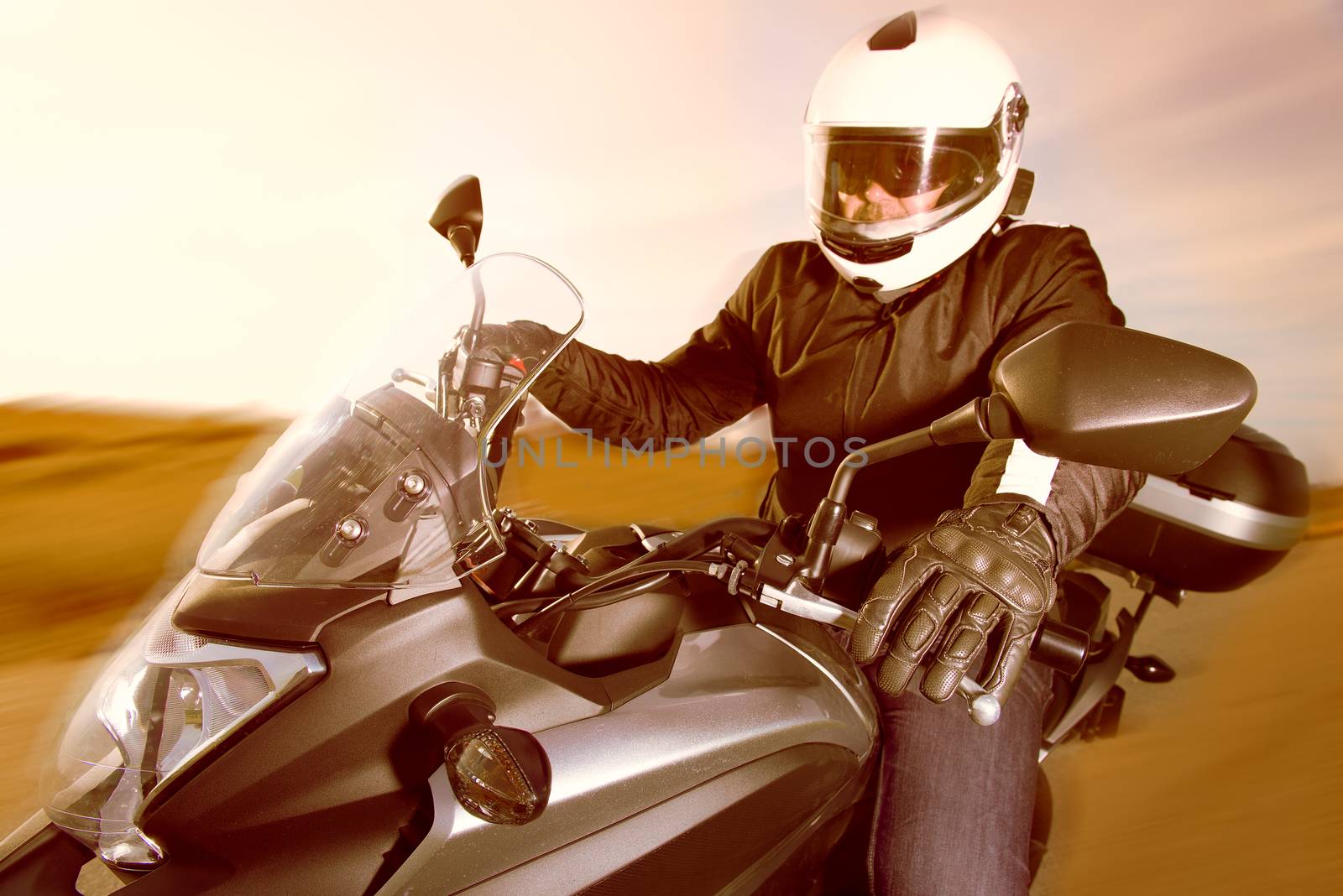 Biker in helmet and leather jacket riding on the road.